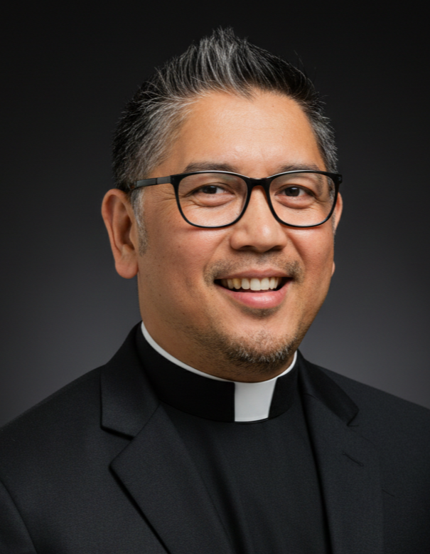 Portrait of a smiling man wearing glasses and a priest's collar against a dark background.