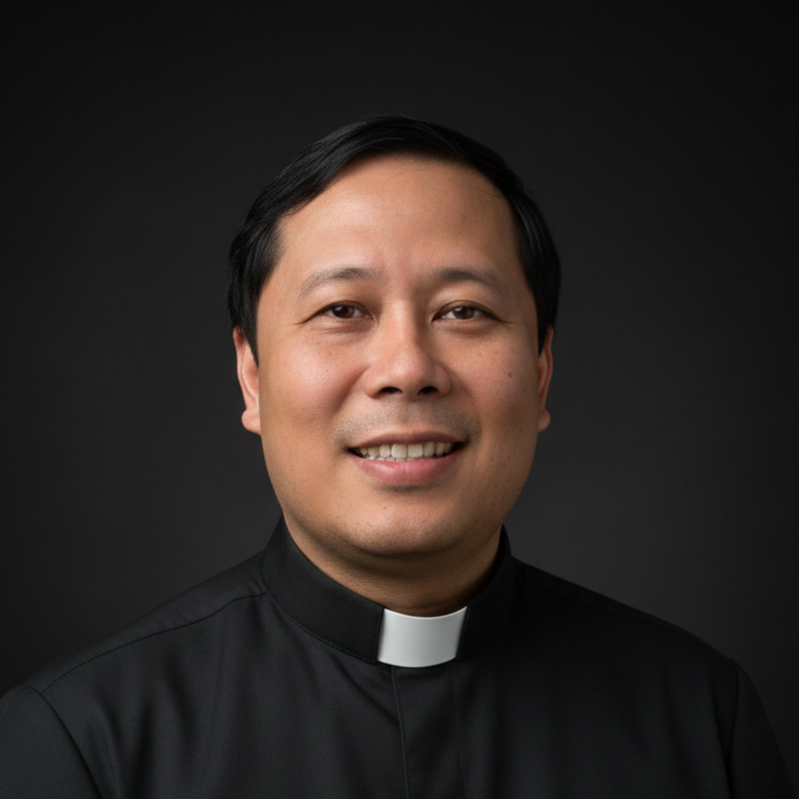 Portrait of a smiling man wearing a black clerical shirt with a white collar, dark background.