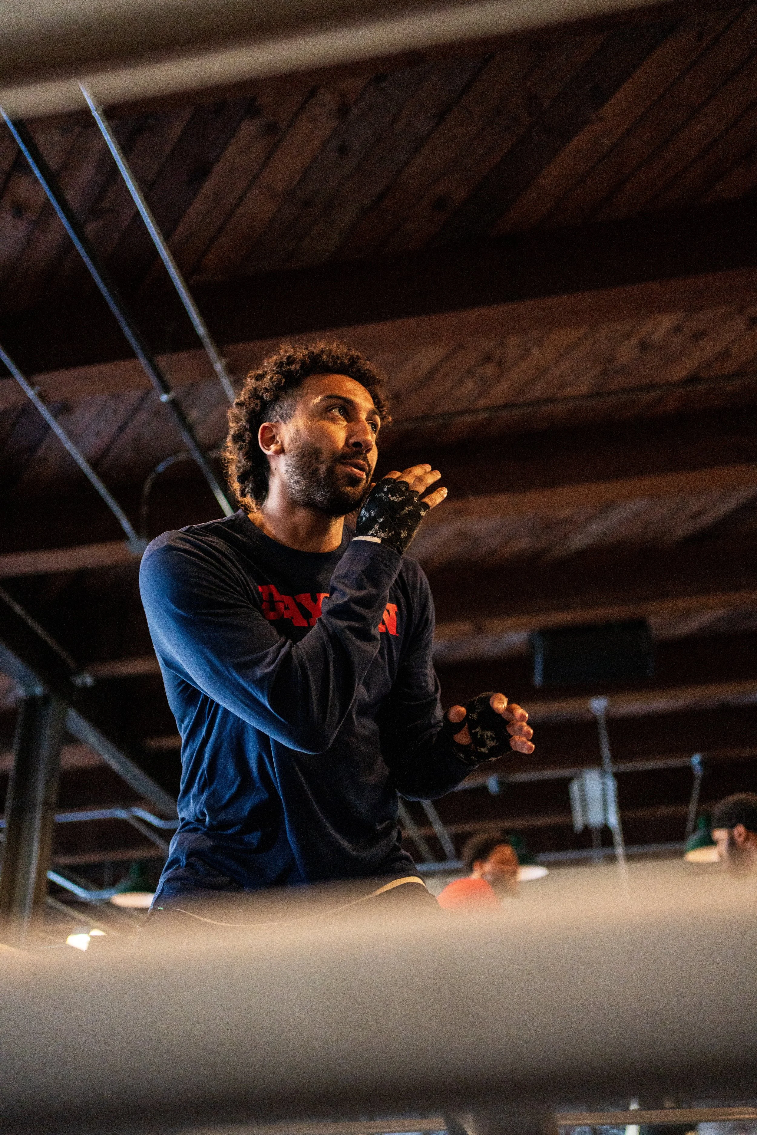 African American man inside a boxing ring demonstrating some boxing fundamentals. he has one had up by his face ready to parry a blow from his opponent mentals