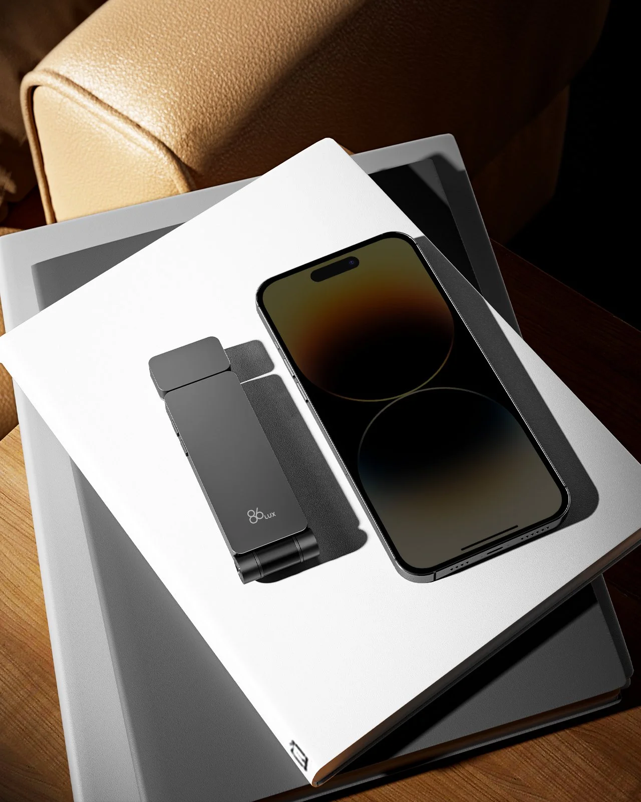 A new iPhone with a dark screen placed on top of an open box with a charger and accessories inside, on a white table with a chair nearby.
