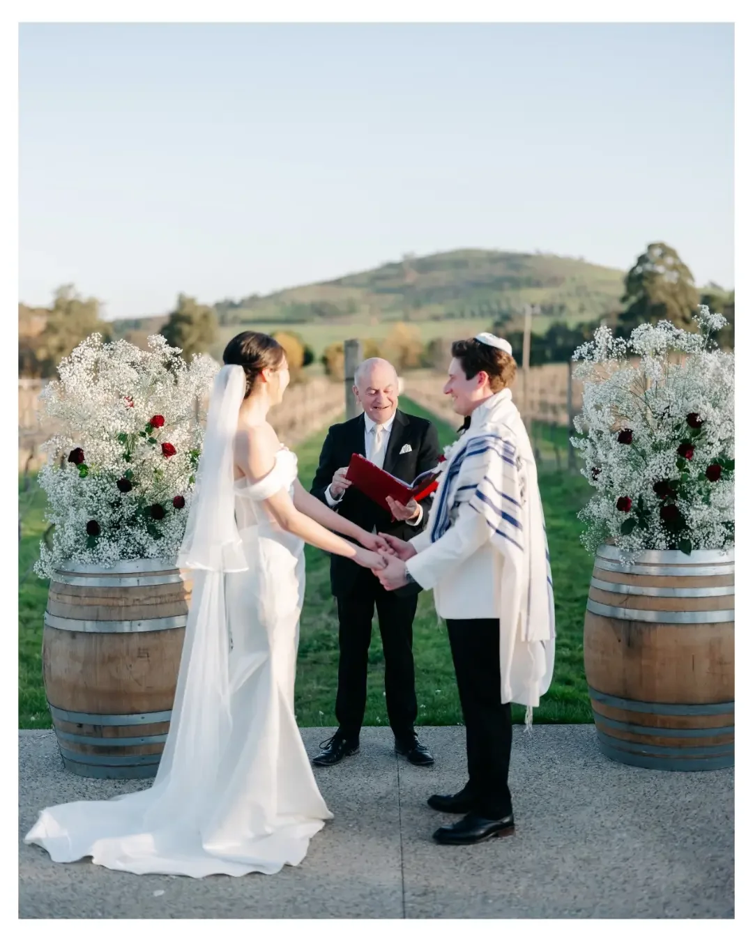 Outdoor vineyard wedding ceremony with a bride and groom exchanging vows in front of their celebrant