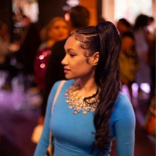 An image of Micheline Erbes in a blue outfit looking to the side of the camera.