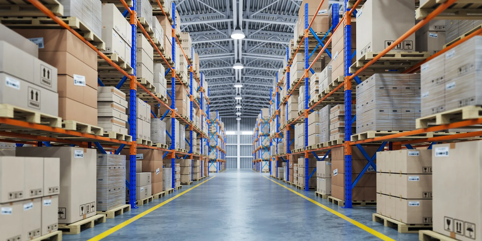 Warehouse storage with shelves filled with boxes and pallets, brightly lit with overhead lights.
