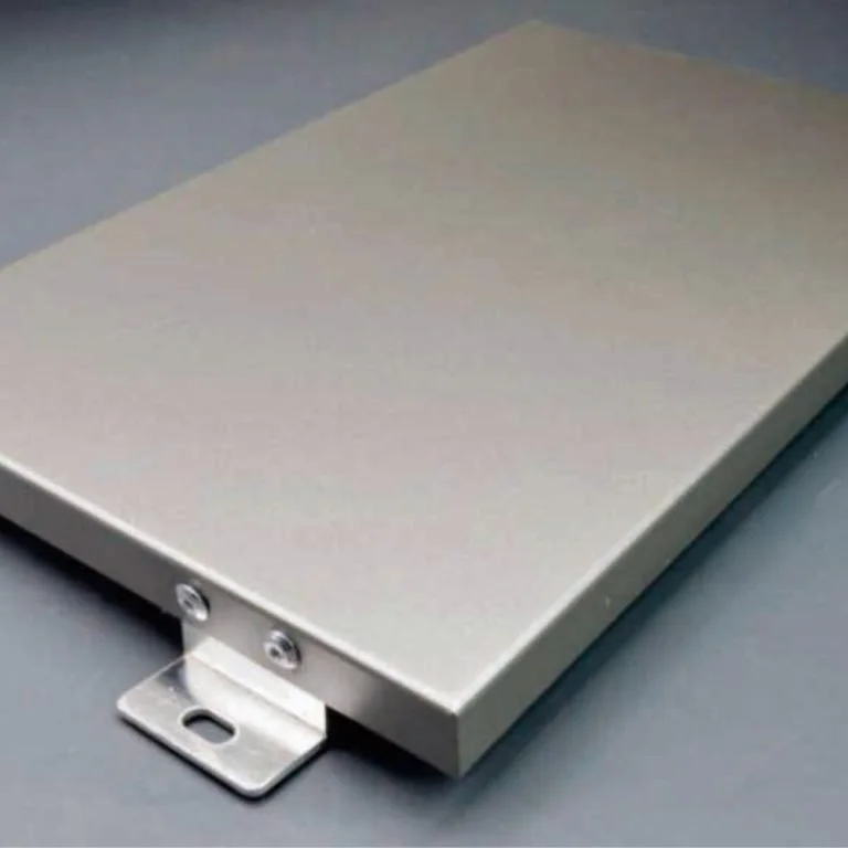 Panneau métallique rectangulaire sur une surface grise avec un support de fixation visible sur le bord.