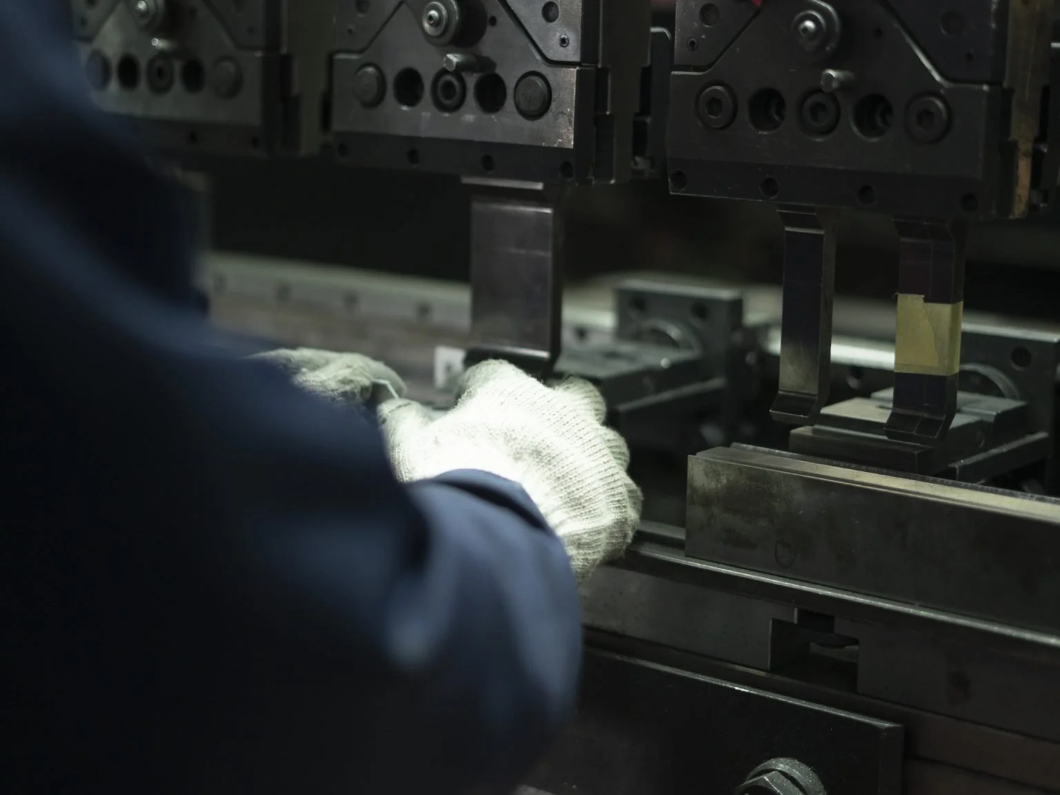 Ouvrier portant des gants travaillant avec une machine industrielle dans une usine.