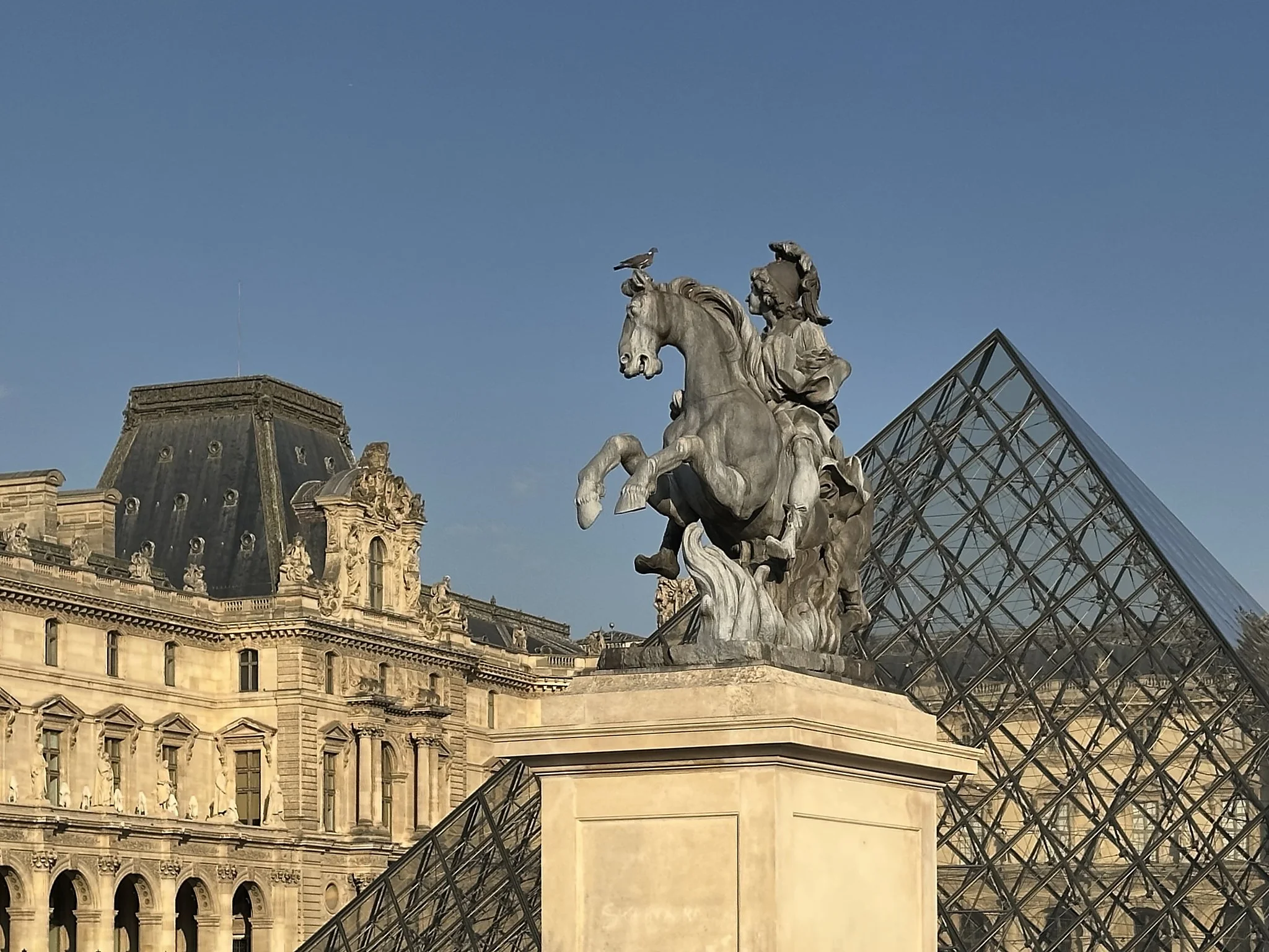 Statue équestre devant le Louvre et sa pyramide en verre, Paris.