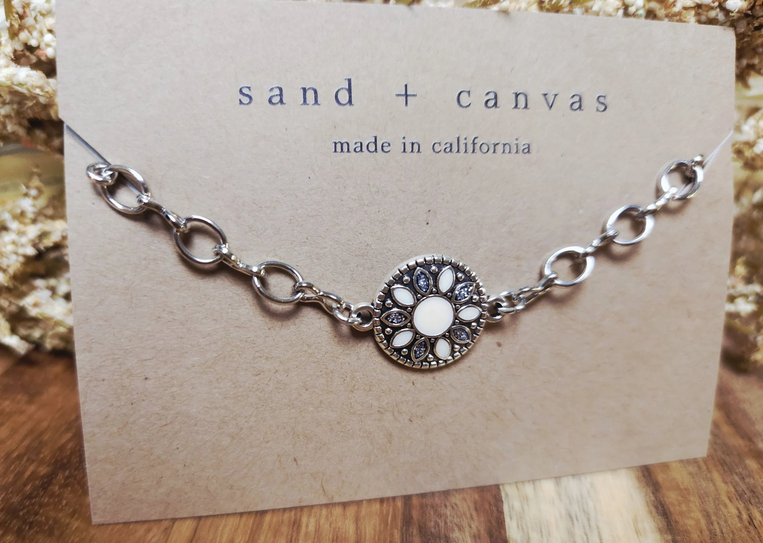 concho bracelet on a lightweight chain resting on the product tag with floral and wood in the background