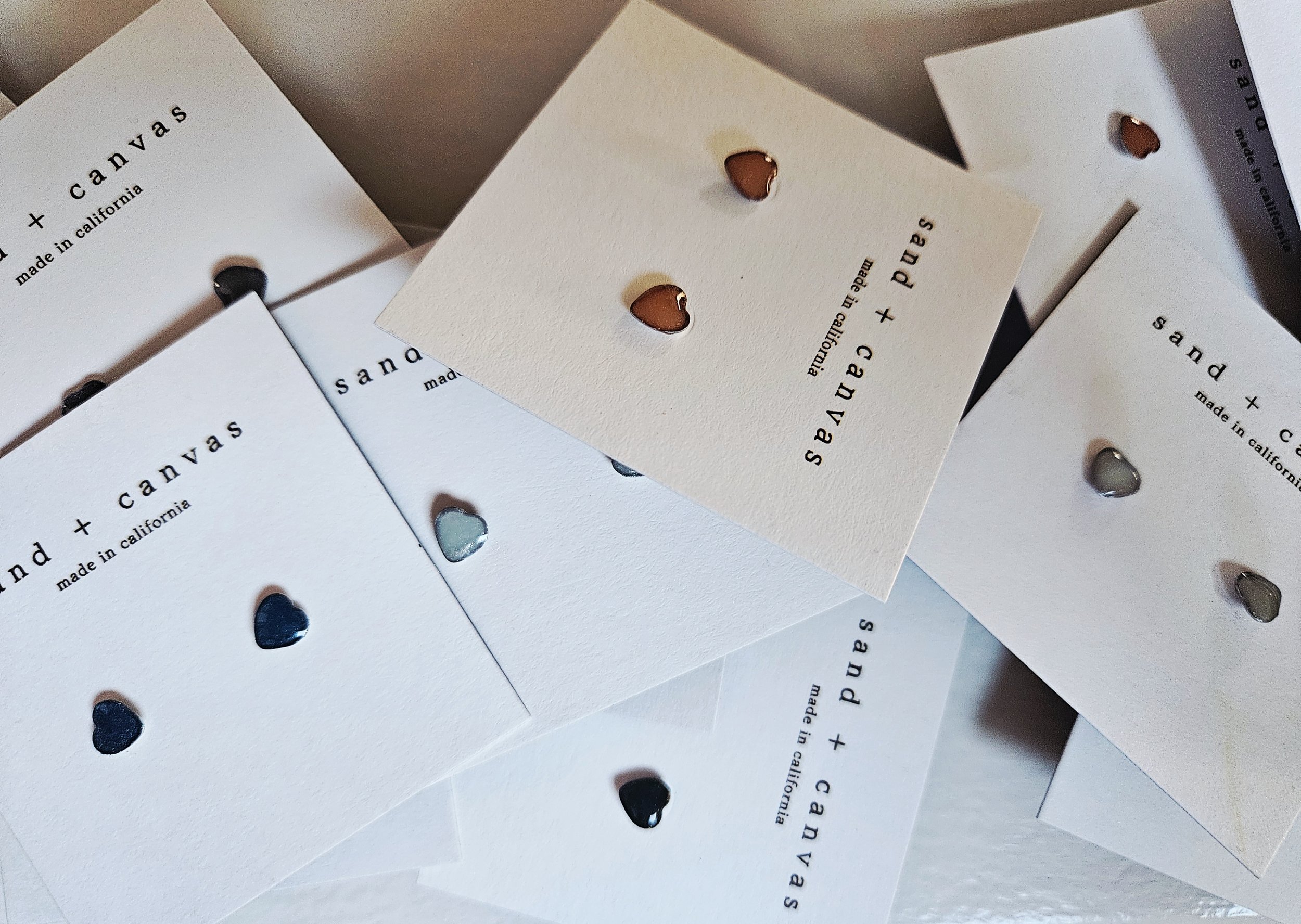 Multi colored heart earrings on white cards from sand and canvas