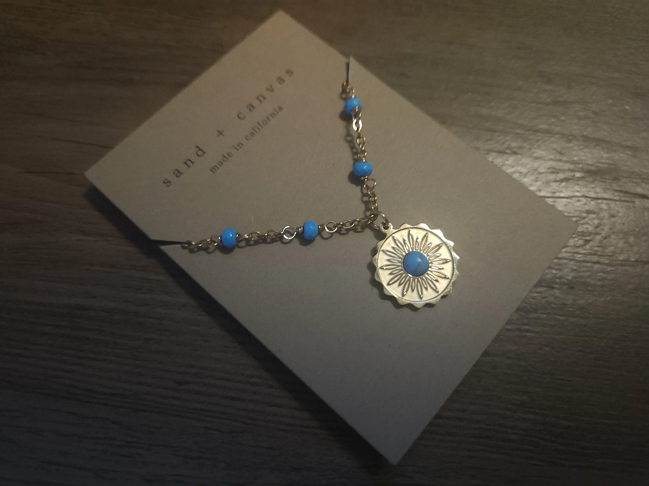 Gold necklace with a gold pendant with blue howlite beads