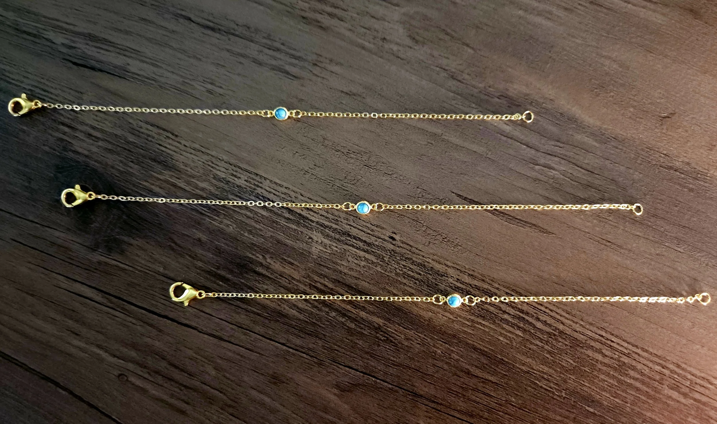 gold bracelets with turquoise dainty pendant on wood background