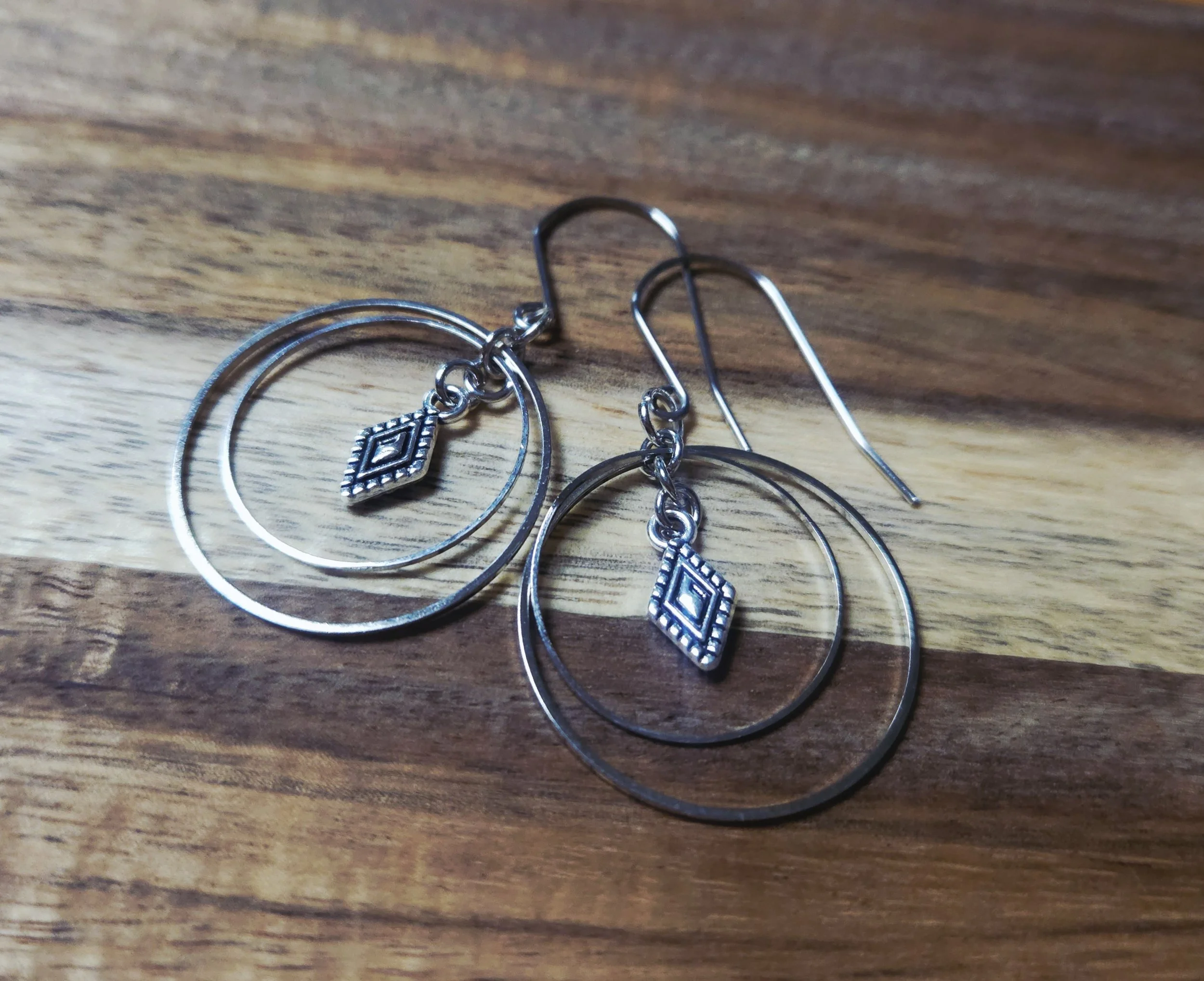 Silver earrings on wood surface
