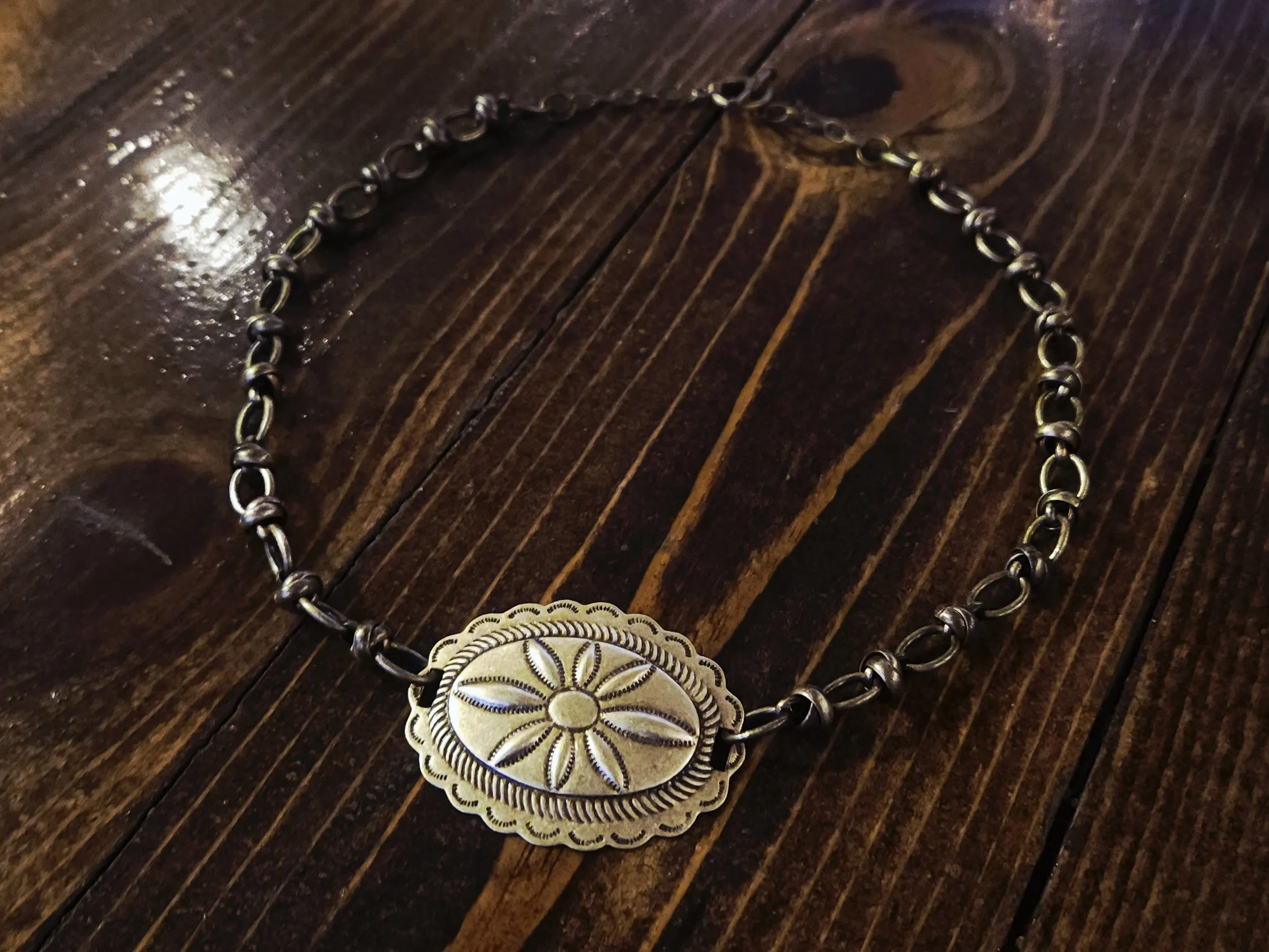 Brass concho necklace on a wood background