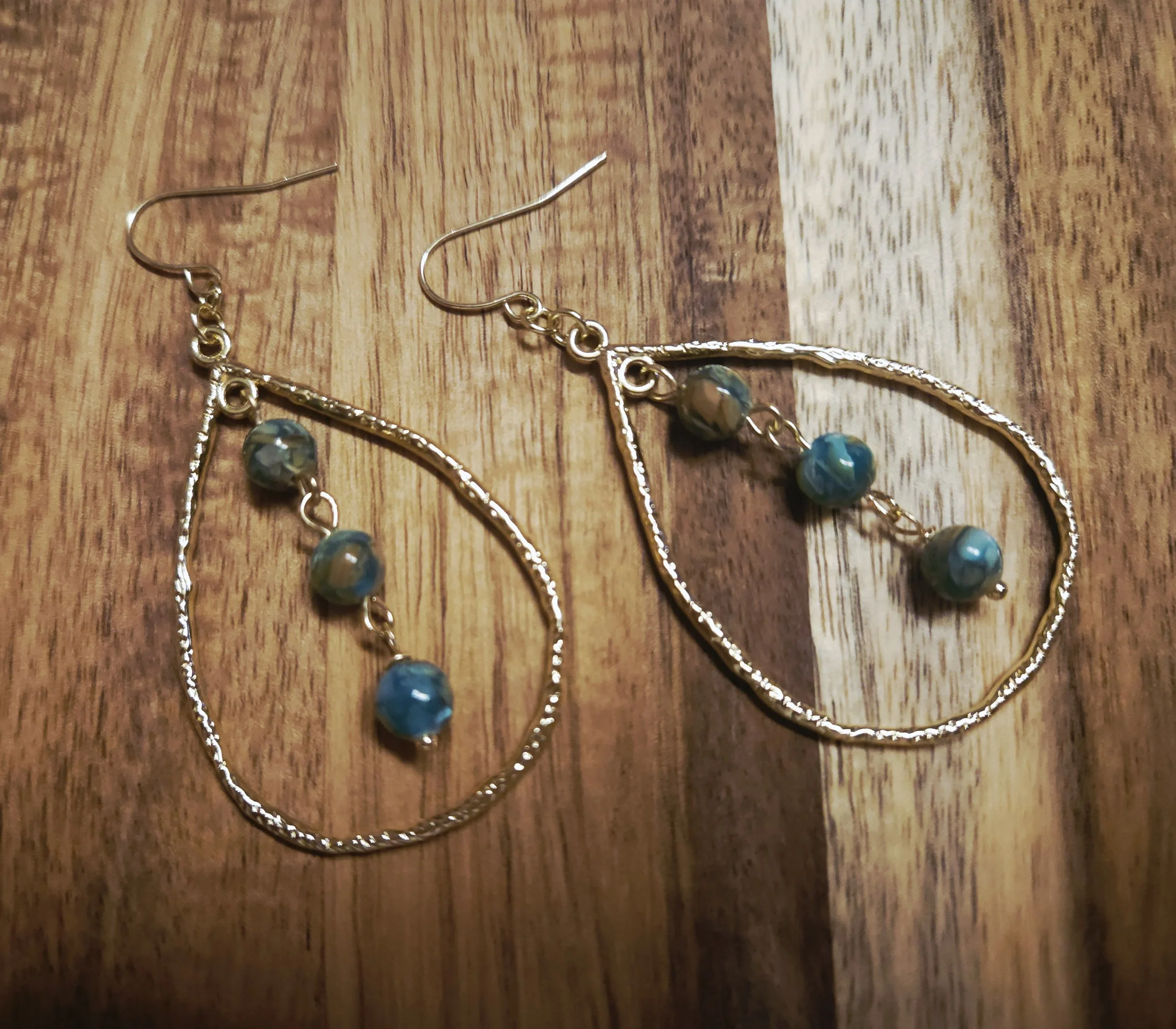 teardrop earrings that are gold colored with green shell mosaic beads in the center