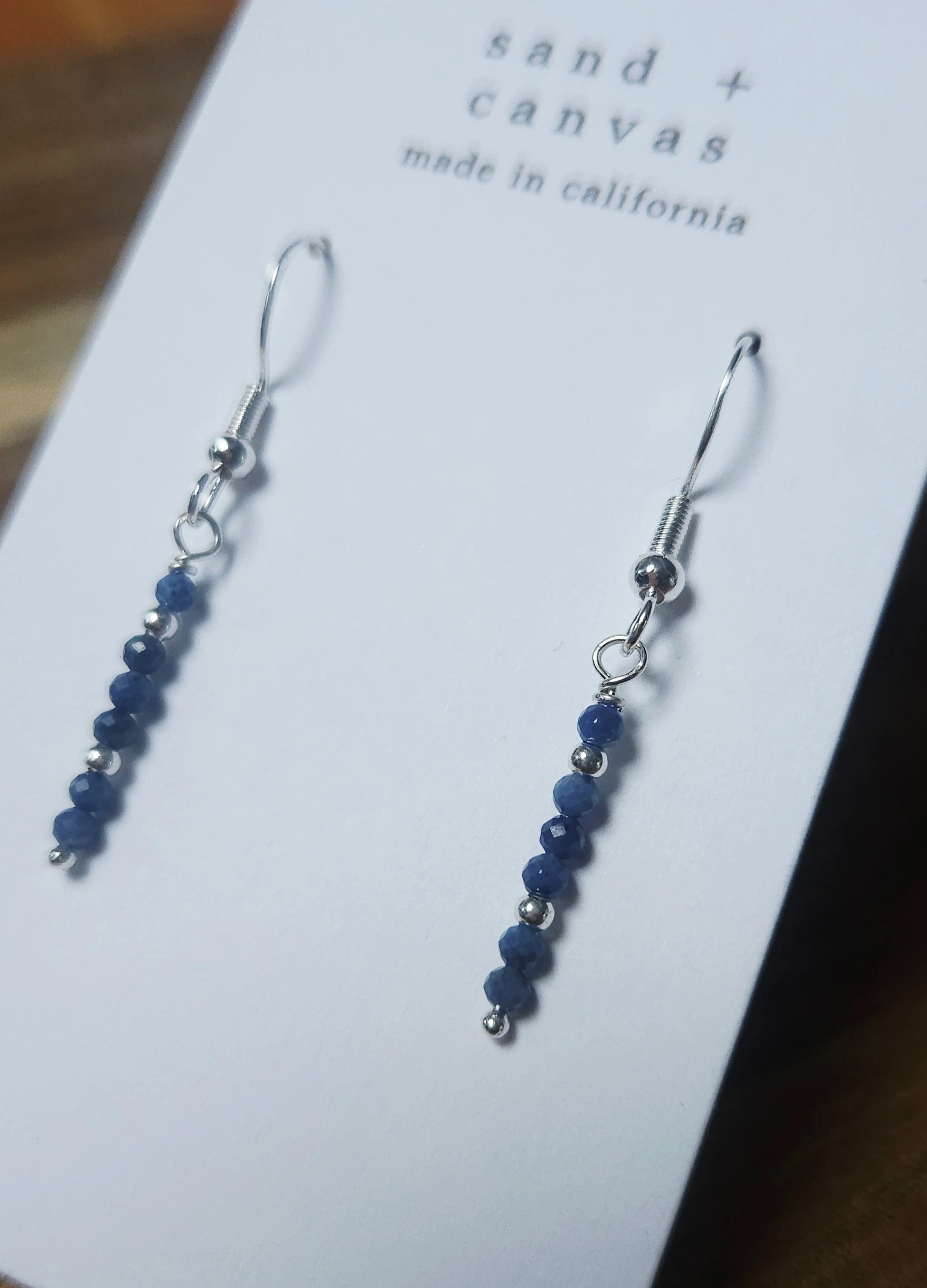 sterling silver earrings with blue sapphire on a brown table
