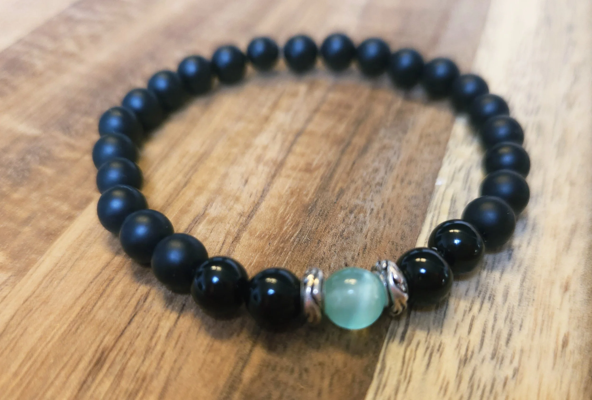 black and green chakra bracelet on table