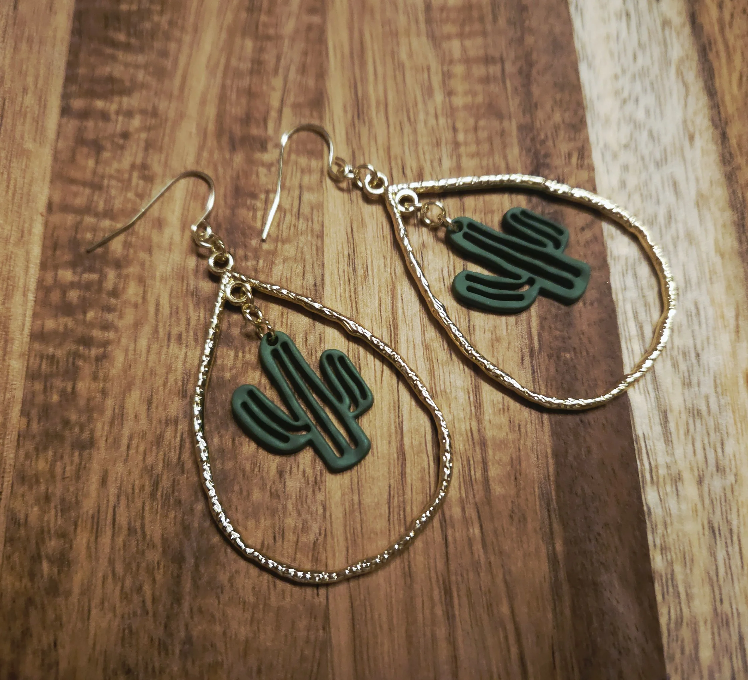 Gold teardrop earrings with a green cactus in the center