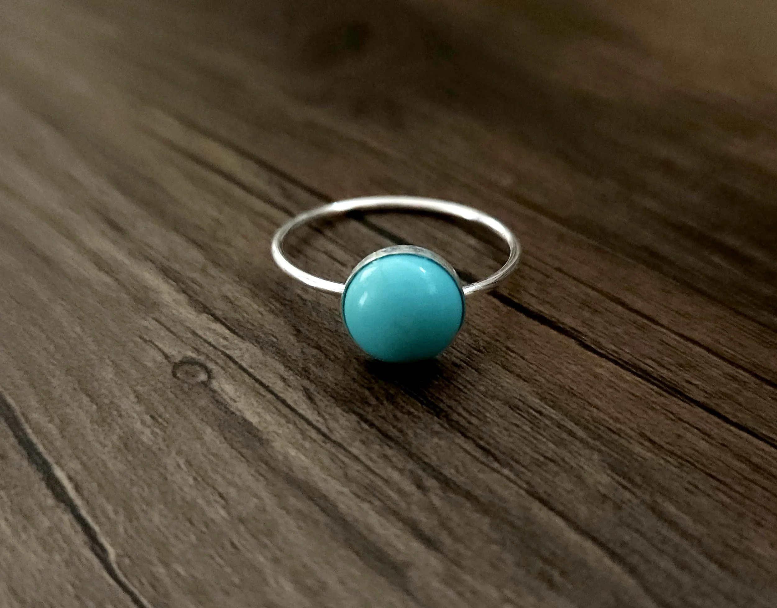 Turquoise and silver ring on a wood table