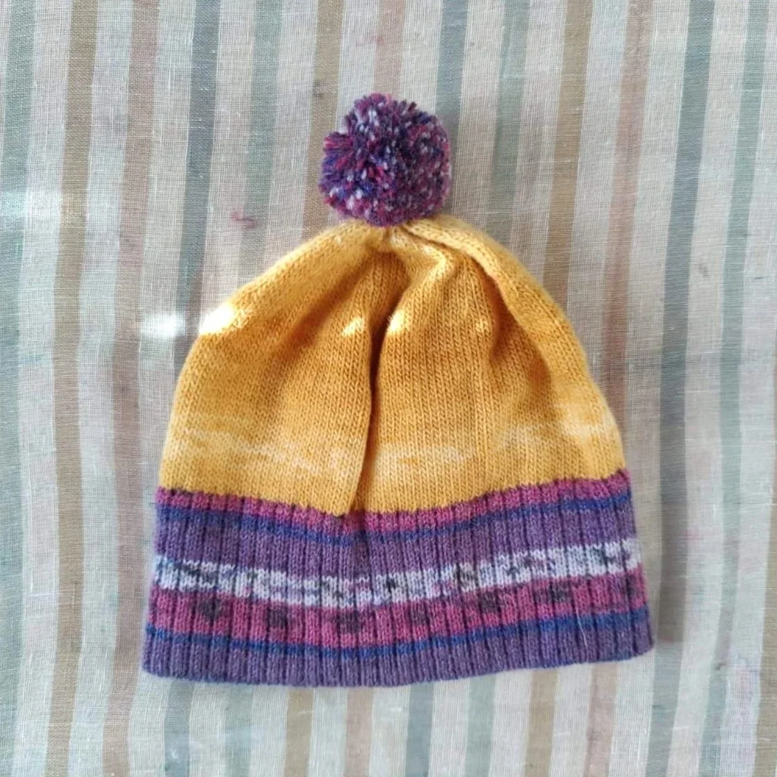 Bonnet artisanal tricoté en laine jaune avec pompon et revers violets à motifs pour enfant