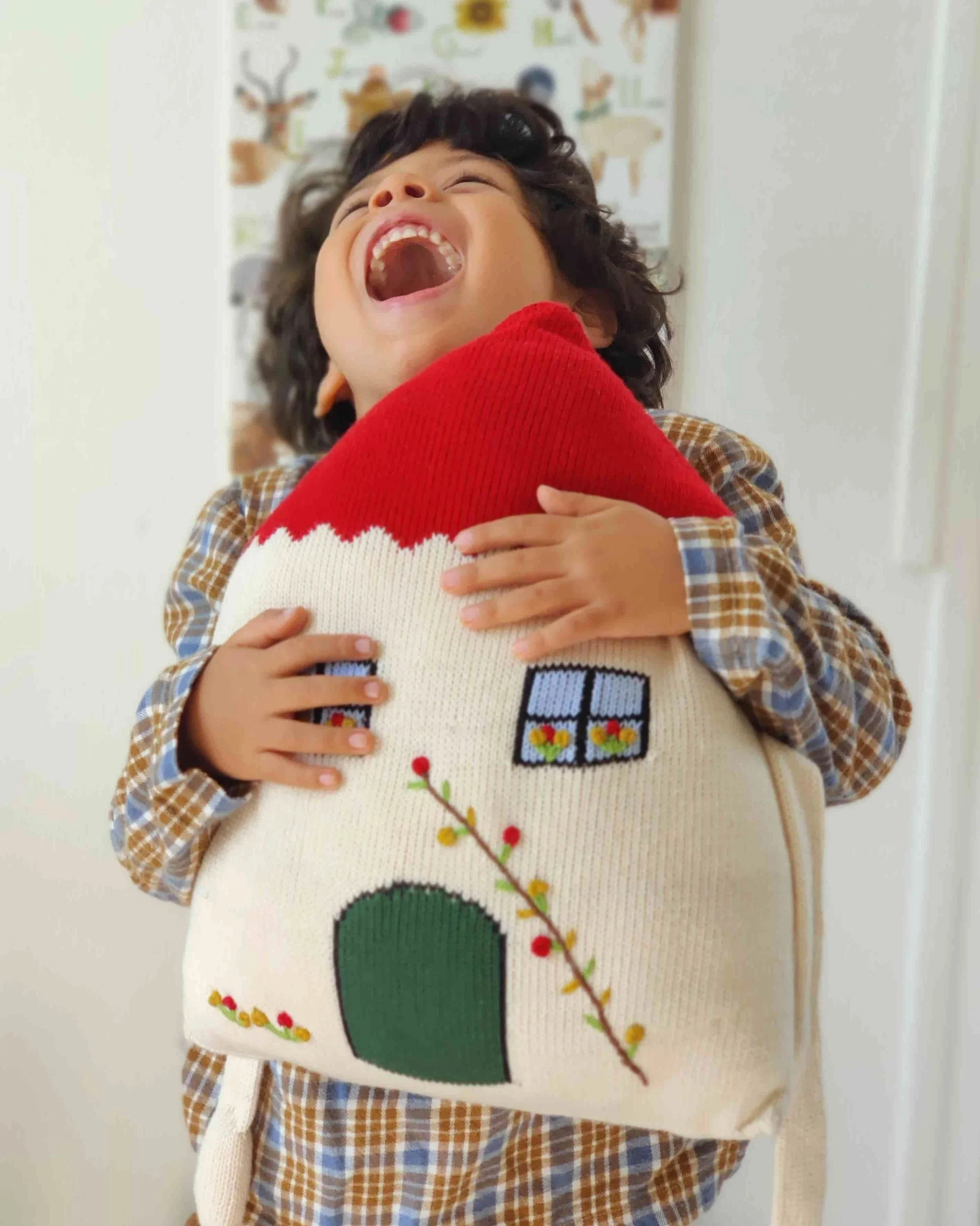 Enfant qui prend dans ses bras le coussin Maison du Réconfort en coton bio
