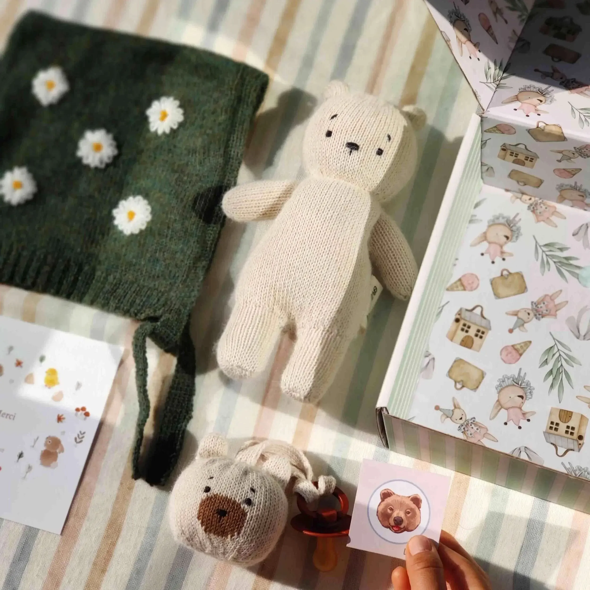 Composition du coffret naissanc eAlpaga neige : un ourson Teddy Bear en alpaga blanc, un mini-Teddy attache-tétine en alpaga blanc et un bonnet béguin vert avec broderies de marguerites