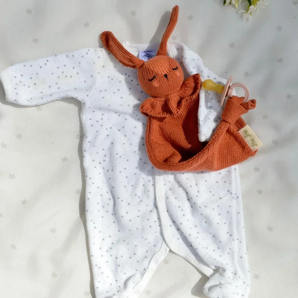 Doudou lapin attache-tétine terracotta avec un vêtement d'enfant