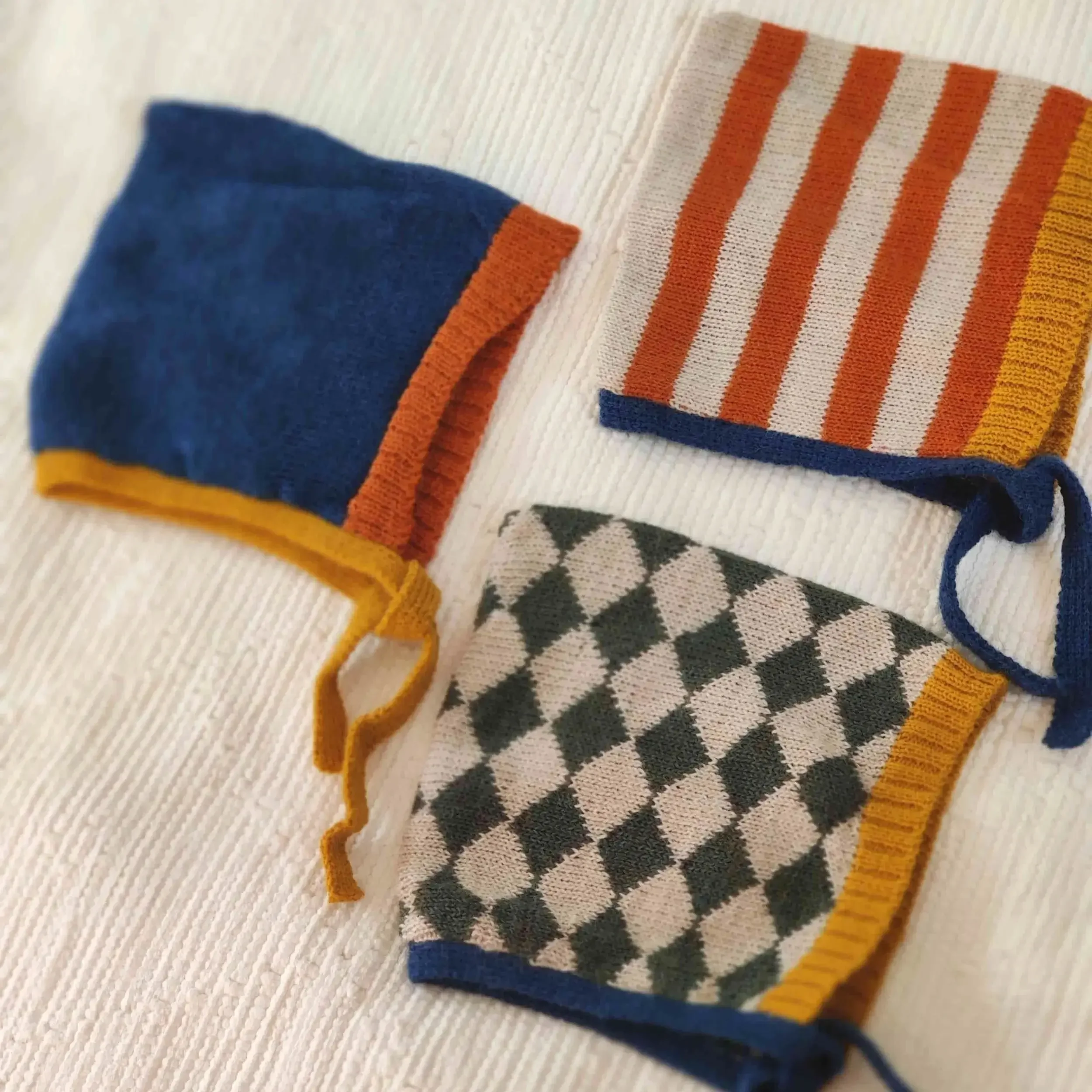 Trois modèles de bonnet béguin pour bébé tricoté artisanalement en alpaga avec motif uni ou losanges ou rayures