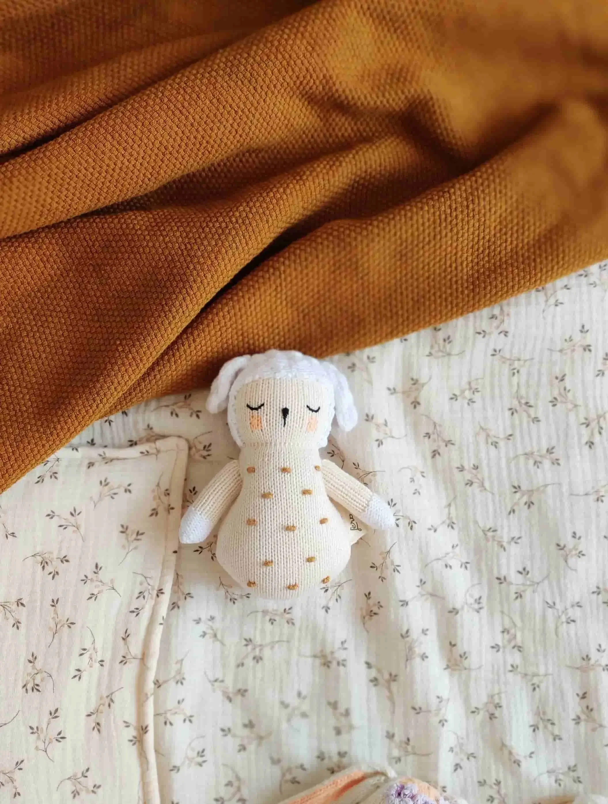 Hochet mouton Nino pour éveiller les nouveau-nés sur un lit