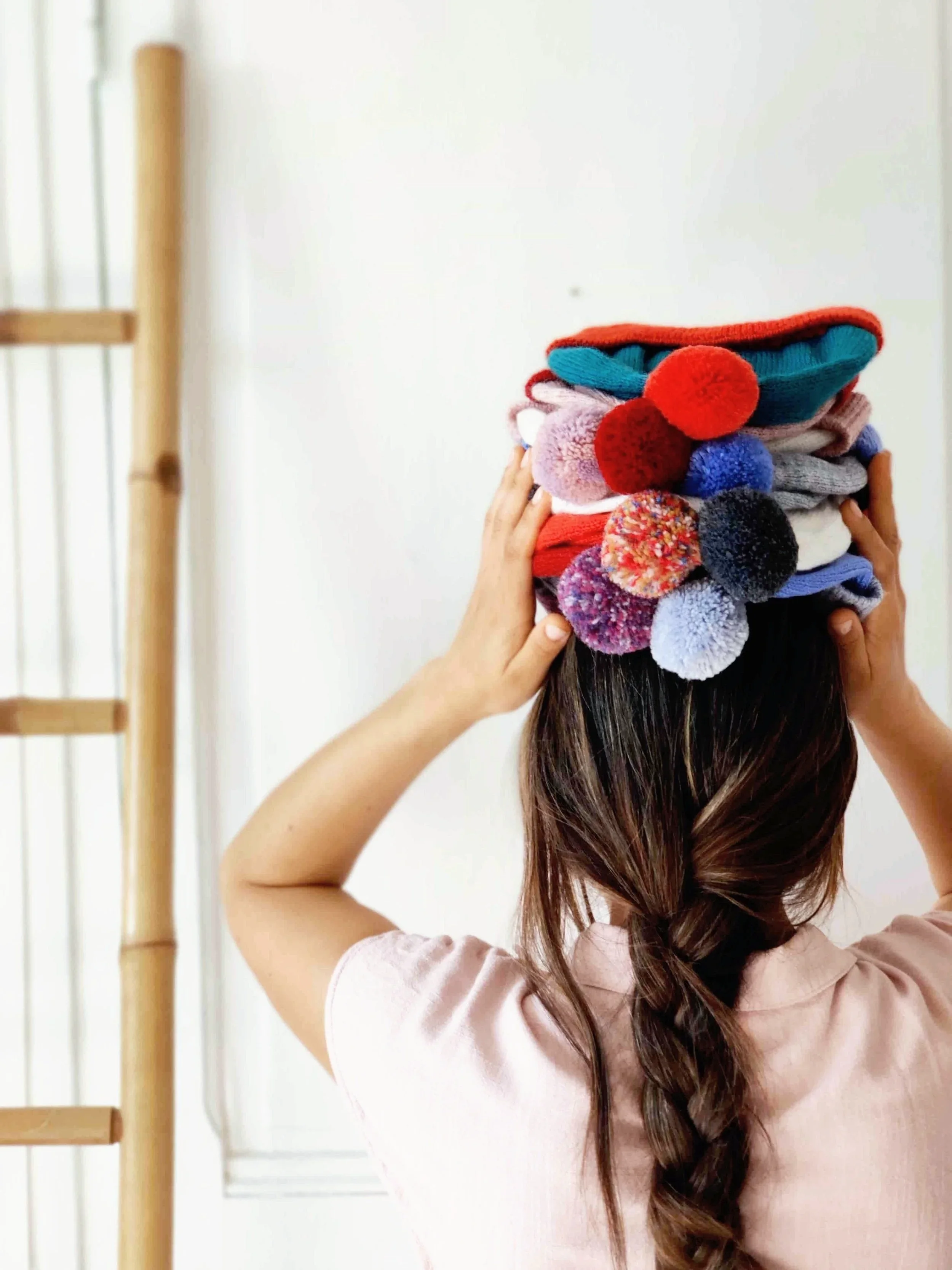 Femme transportant plusieurs modèles de bonnets colorés à pompon tricotés en laine