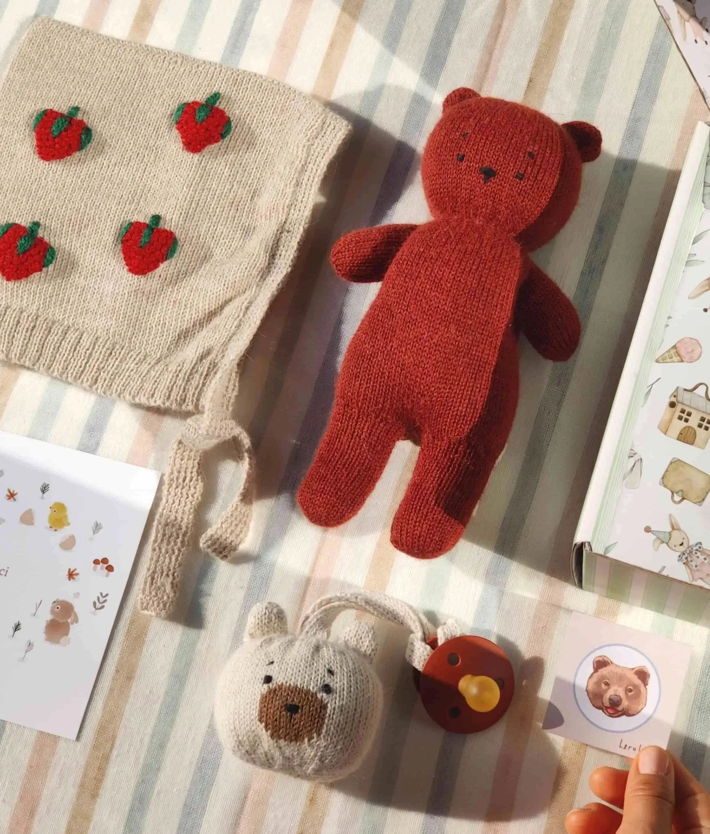 Composition du coffret naissance Alpaga rouge cerise : un ourson Teddy Bear en alpaga terracotta, un mini-Teddy attache-tétine en alpaga blanc et un bonnet béguin blanc avec broderies de fraises