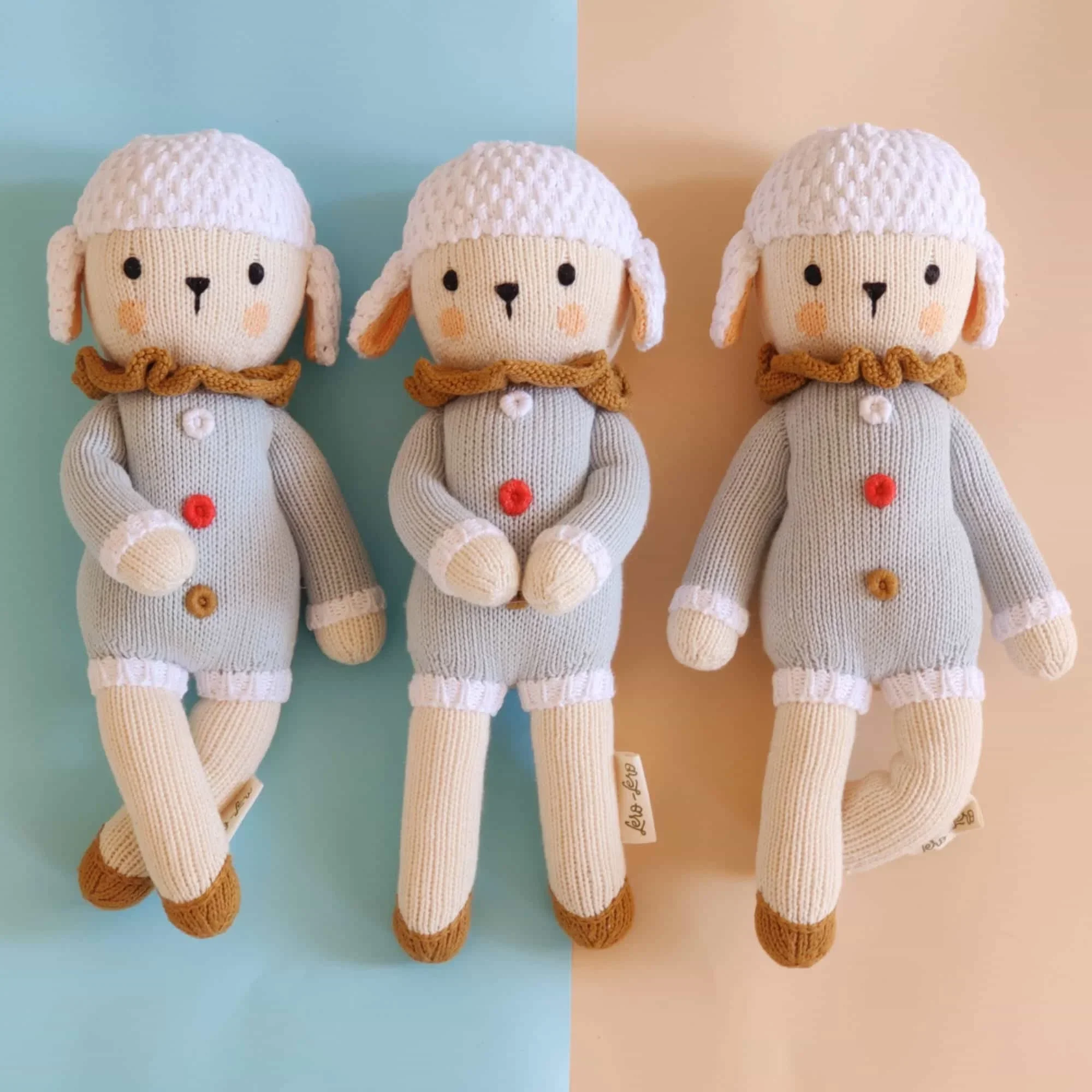 Peluche mouton Nino Rainbow tricotée en coton bio dans 3 positions différentes
