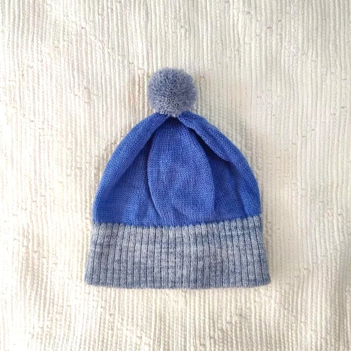 Bonnet artisanal tricoté en laine bleu avec pompon et revers gris pour enfant