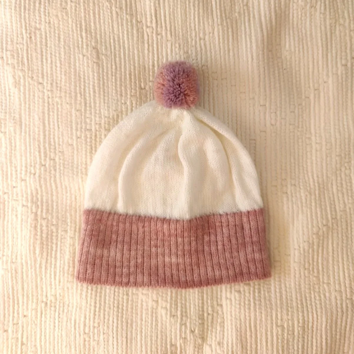 Bonnet artisanal tricoté en laine blanc avec pompon et revers roses pour enfant