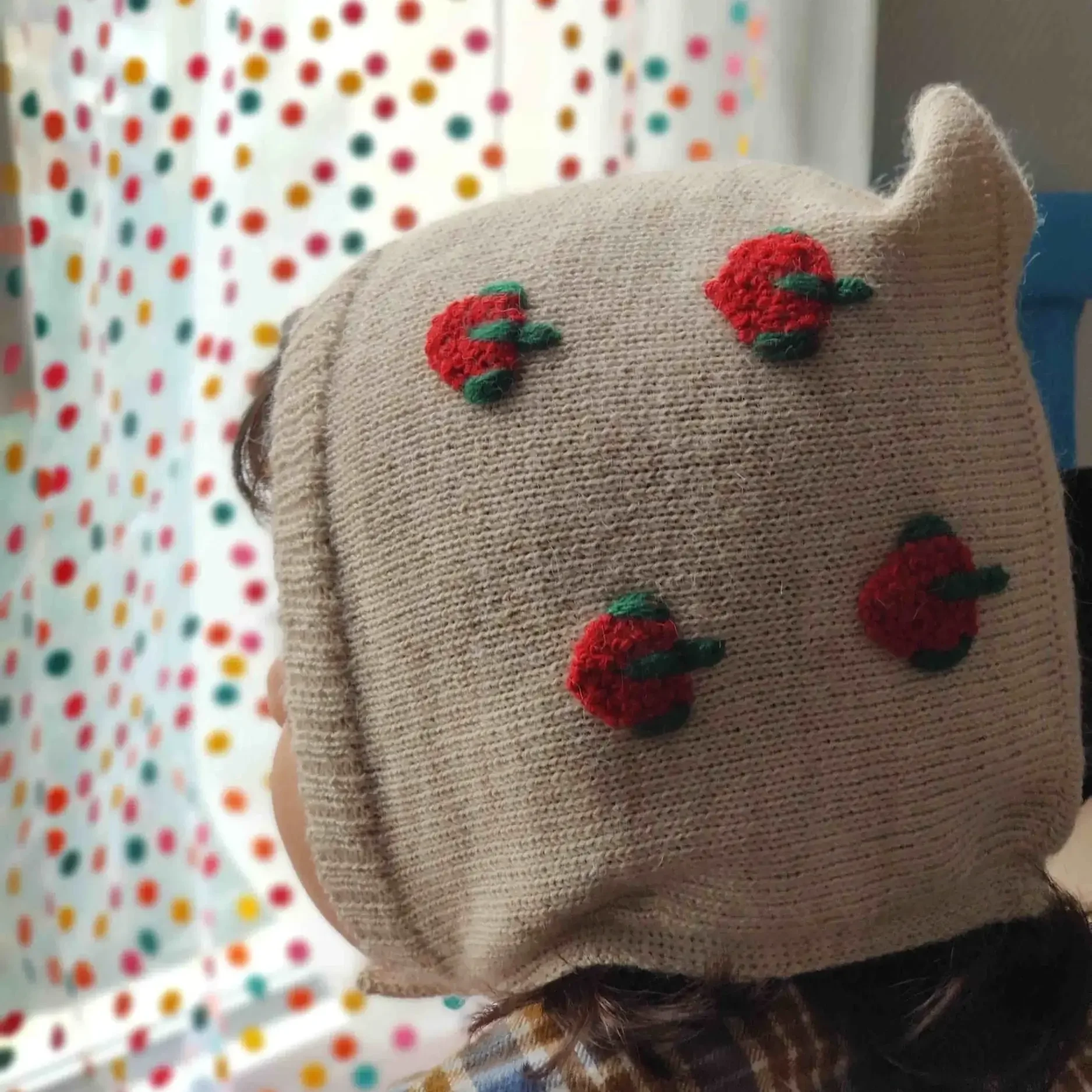 Bébé portant un bonnet béguin en alpaga blanc avec des broderies de fraise