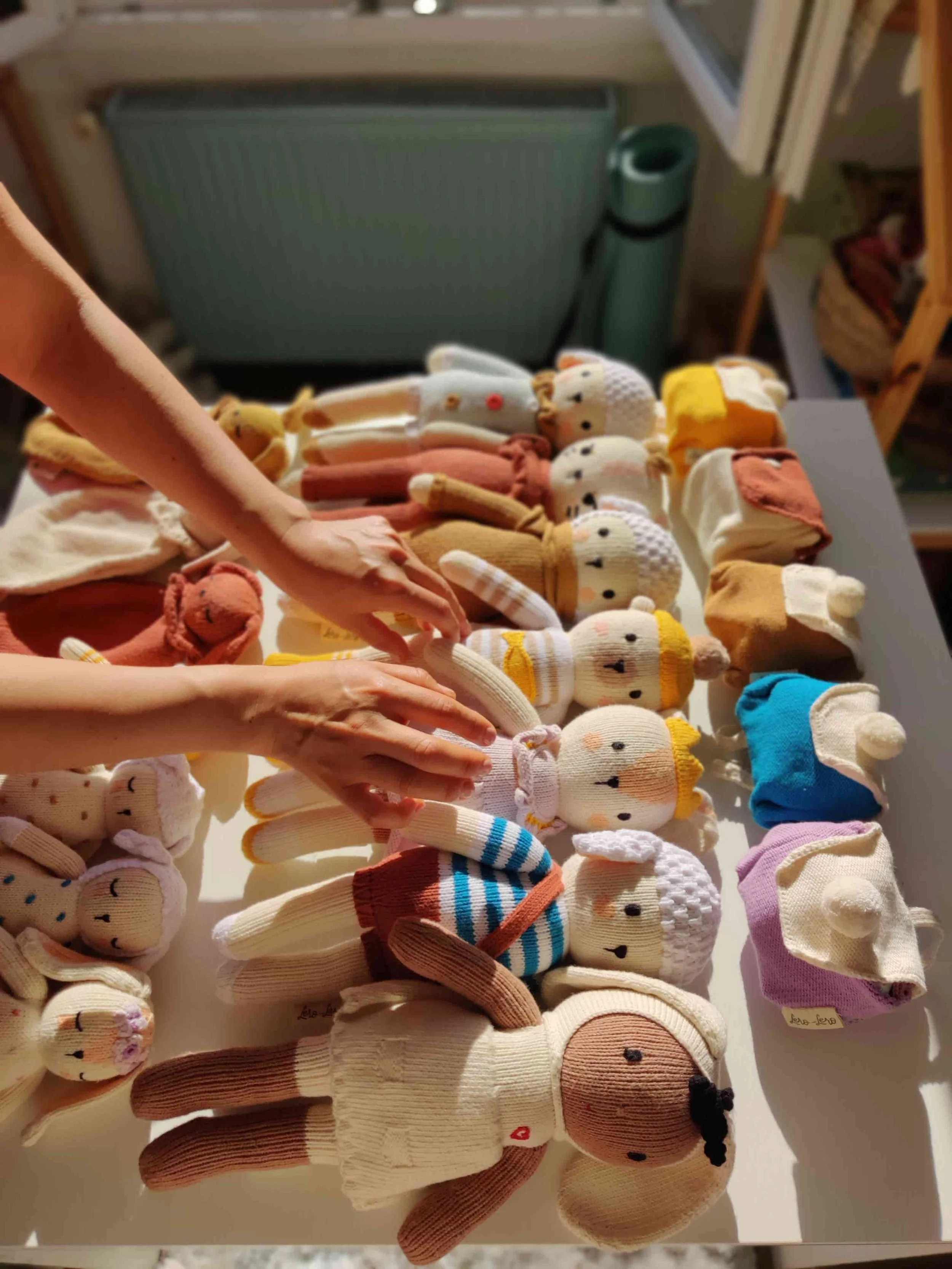Peluches des émotions, hochets et attache-tétines tricotés en coton bio sur la table de la créatrice