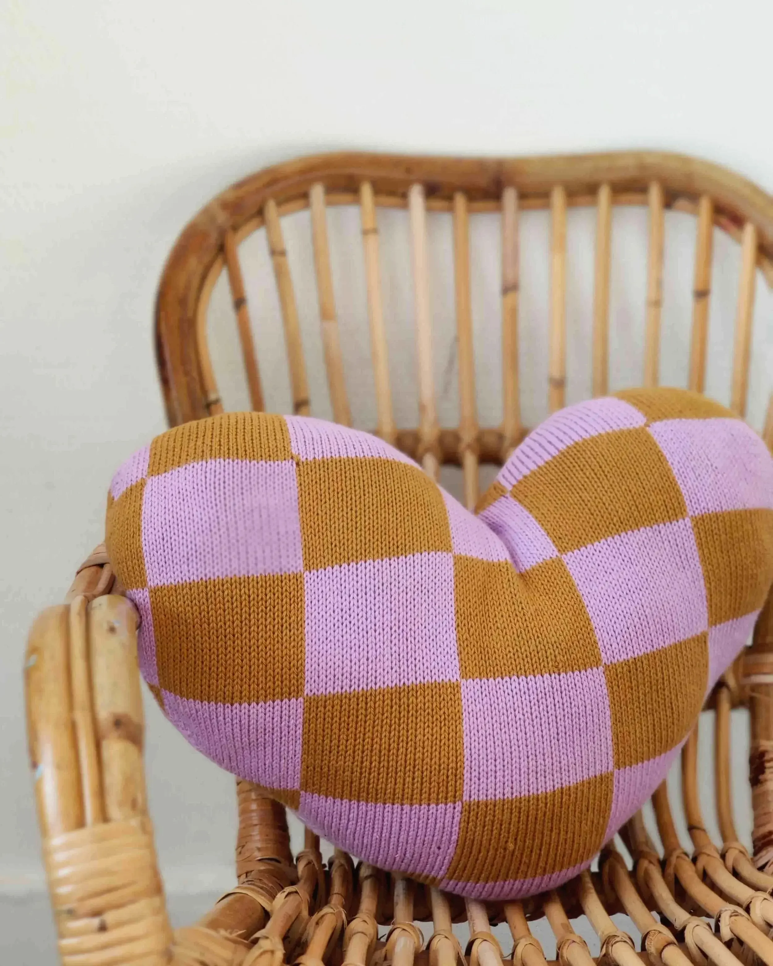 Coussin Coeur tricoté en coton bio, sur une chaise en osier. Cadeau symbolique