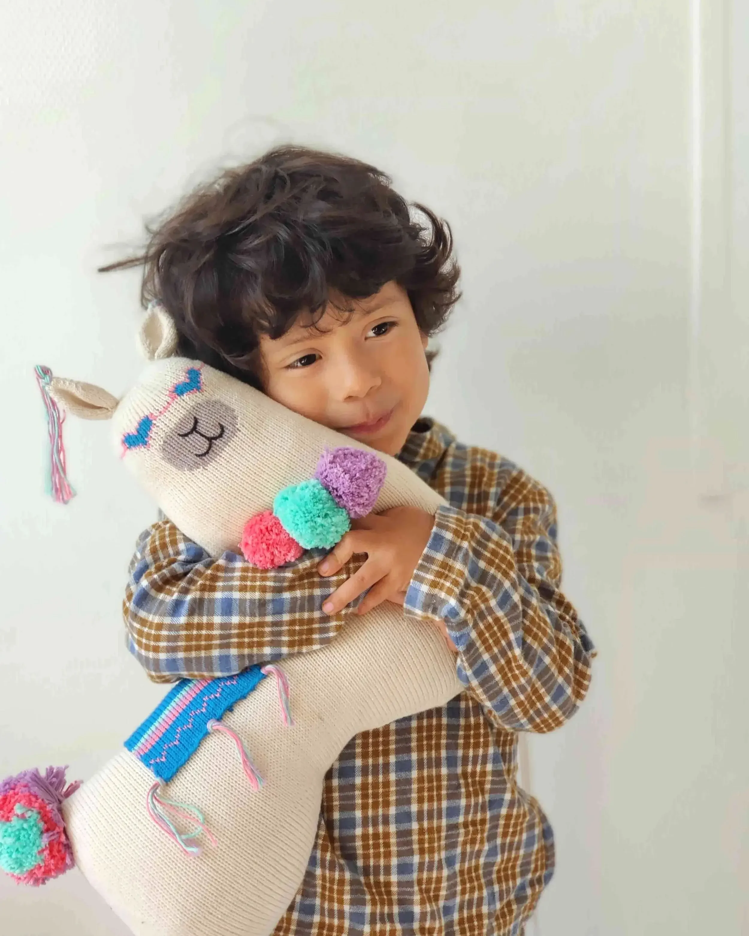 Enfant qui prend dans ses bras le coussin Lama en coton bio