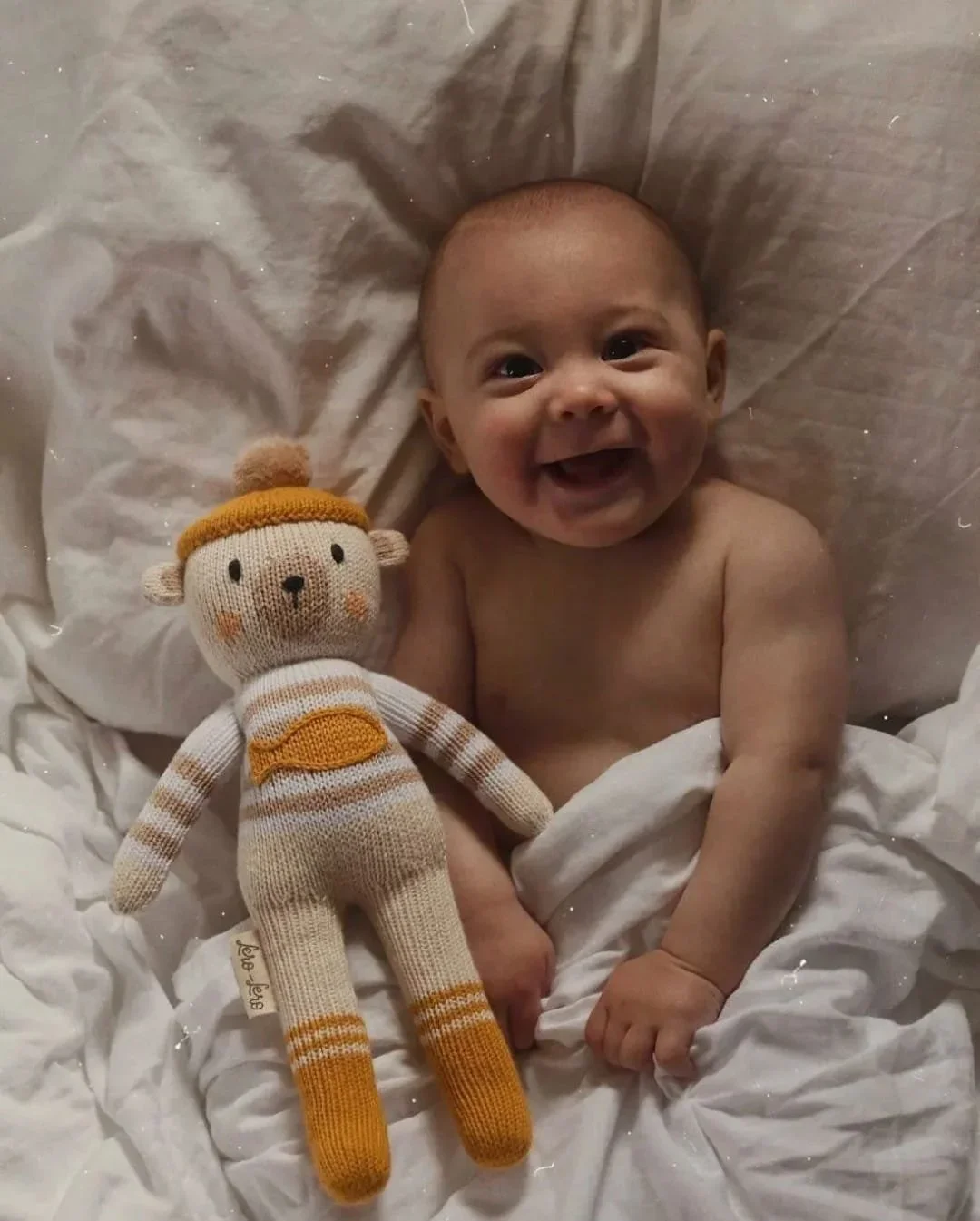 Doudou ours polaire Yaruc dans un lit avec un enfant heureux