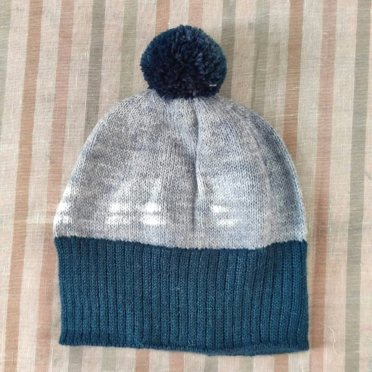 Bonnet artisanal tricoté en laine gris avec pompon et revers bleus-verts pour enfant