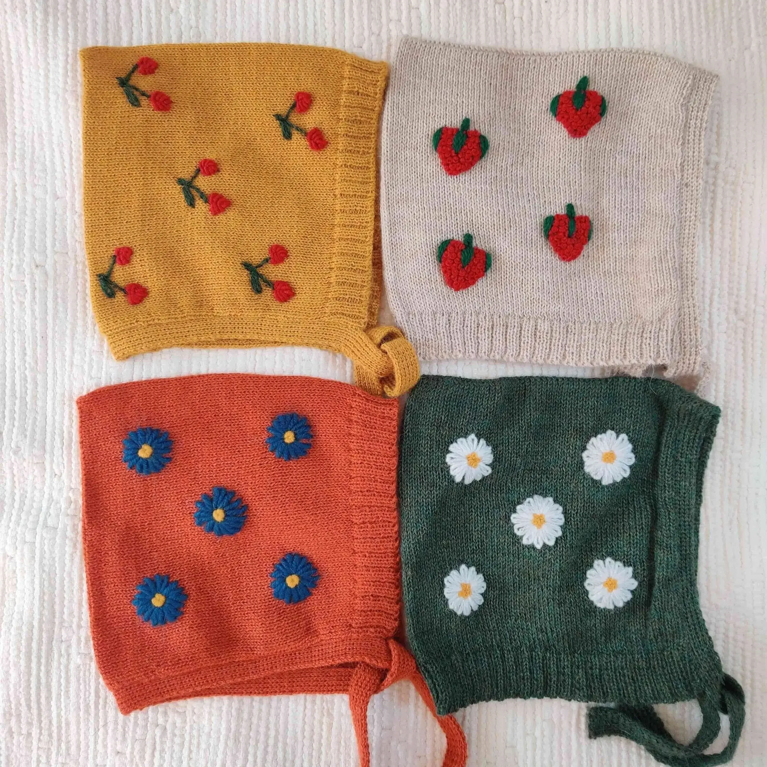 Les quatre modèles de bonnet béguin pour bébé tricotés en alpaga avec broderies