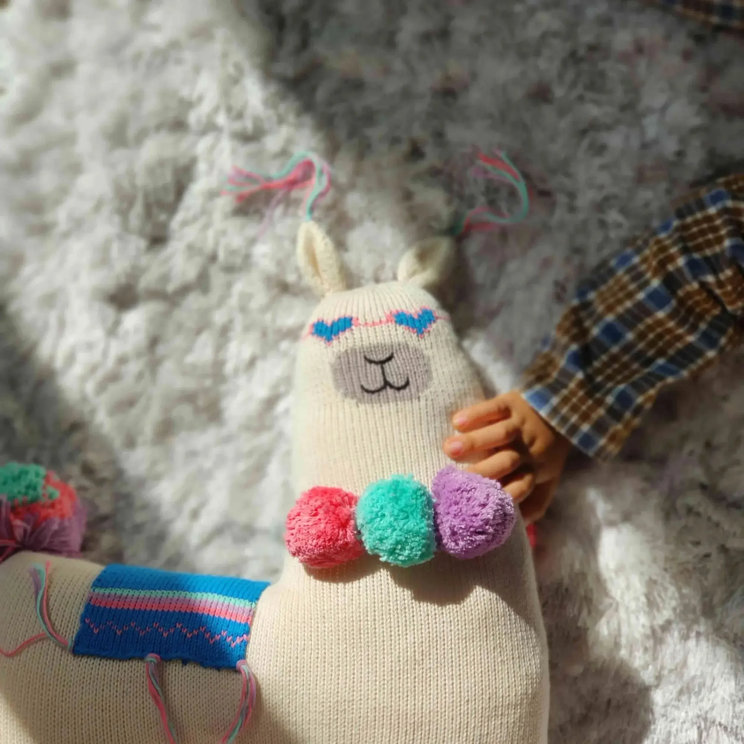 Coussin Lama en coton bio avec une main d'enfant qui essaye de l'attraper