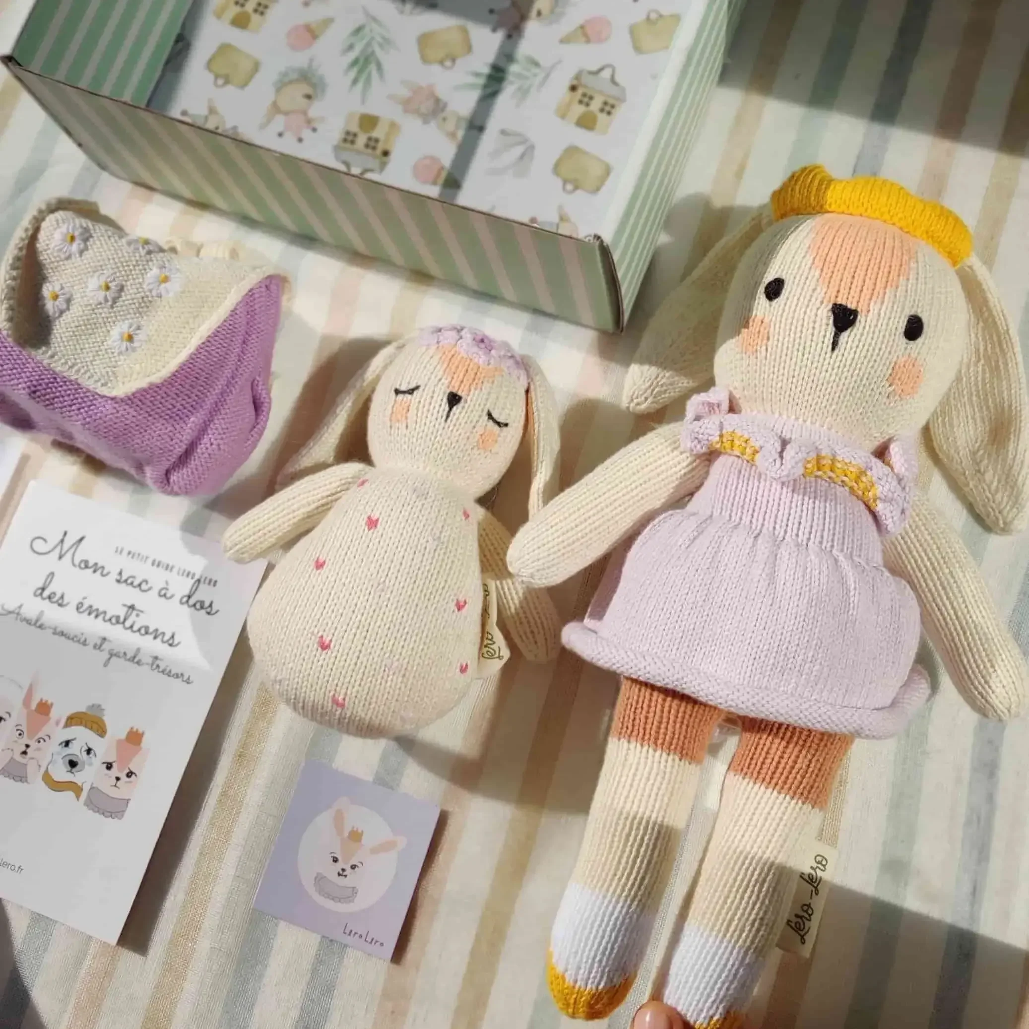 Détail sur la composition du coffret naissance Qori la lapine : peluche Qori, sac à dos des émotions à broderies fleurs et hochet. Tricotés en coton bio.