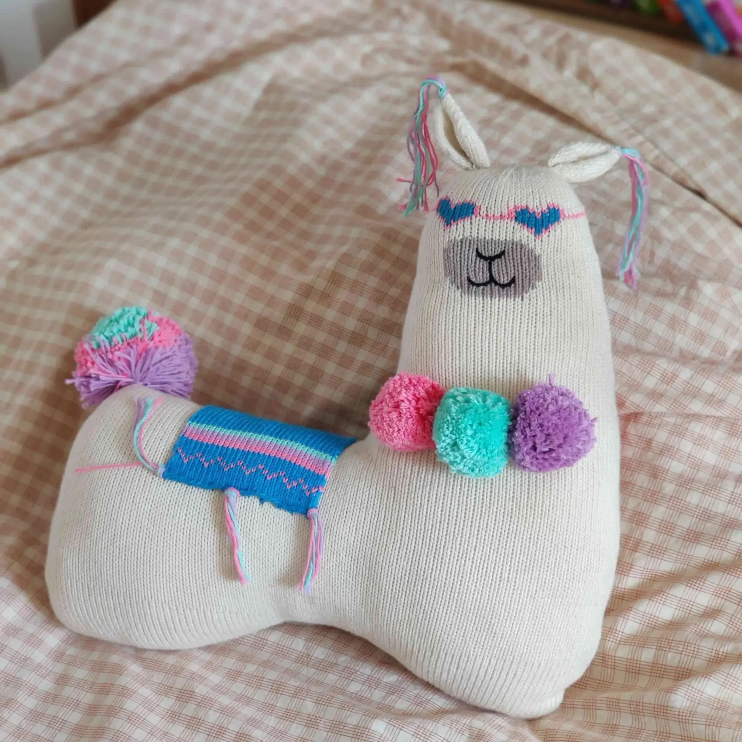 Coussin Lama positionné sur un lit. Cadeau symbolique artisanal.