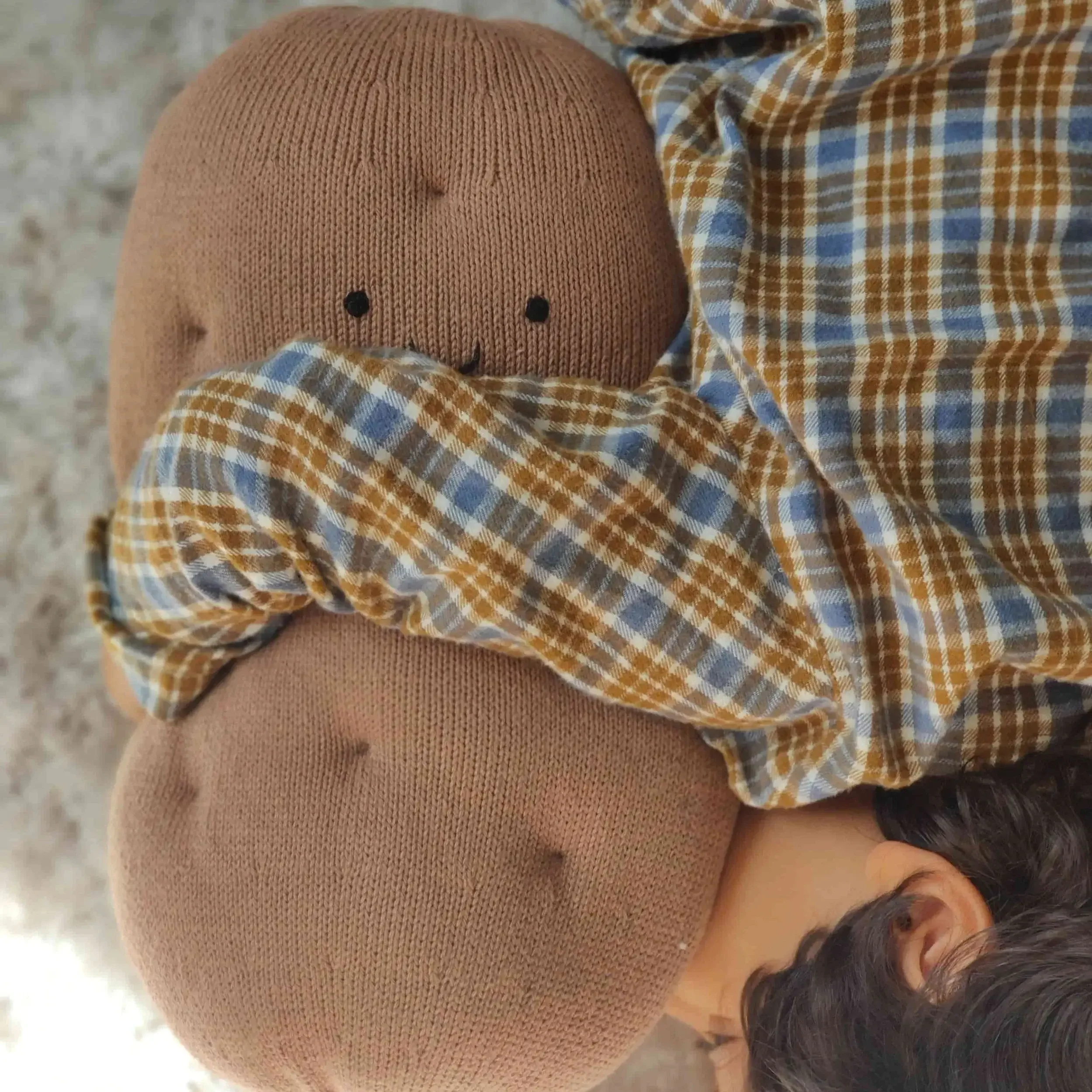 Enfant qui serre dans ses bras le cadeau symbolique coussin Pomme de Terre