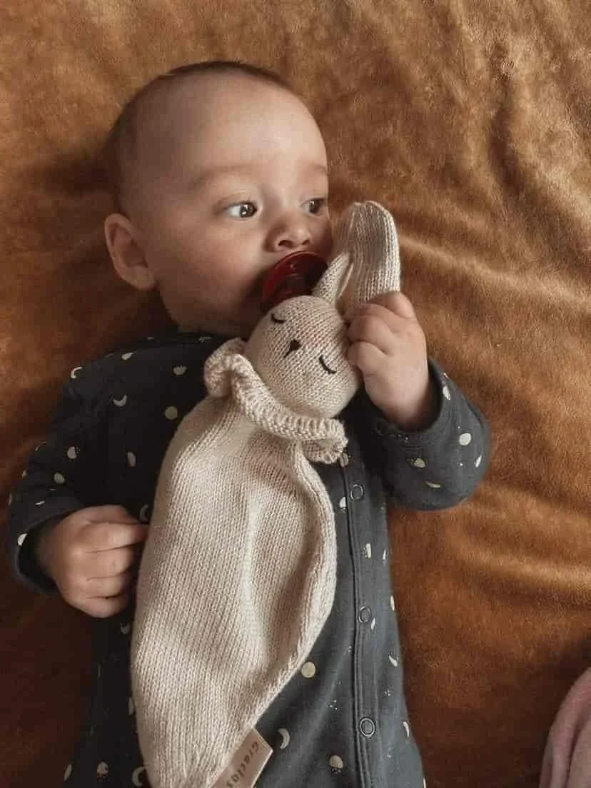 Bébé utilisant le doudou lapin en coton avec sa tétine