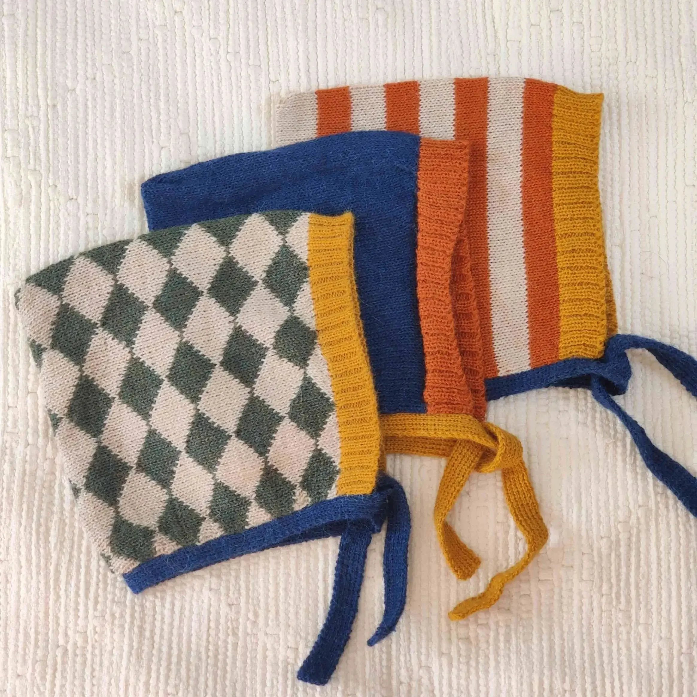 Trois modèles superposés de bonnet béguin pour bébé tricoté en alpaga avec motif uni ou losanges ou rayures