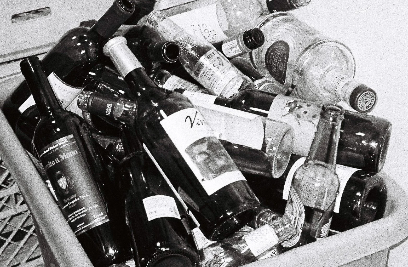 A collection of empty glass bottles, some lying on top of each other, in a plastic crate.