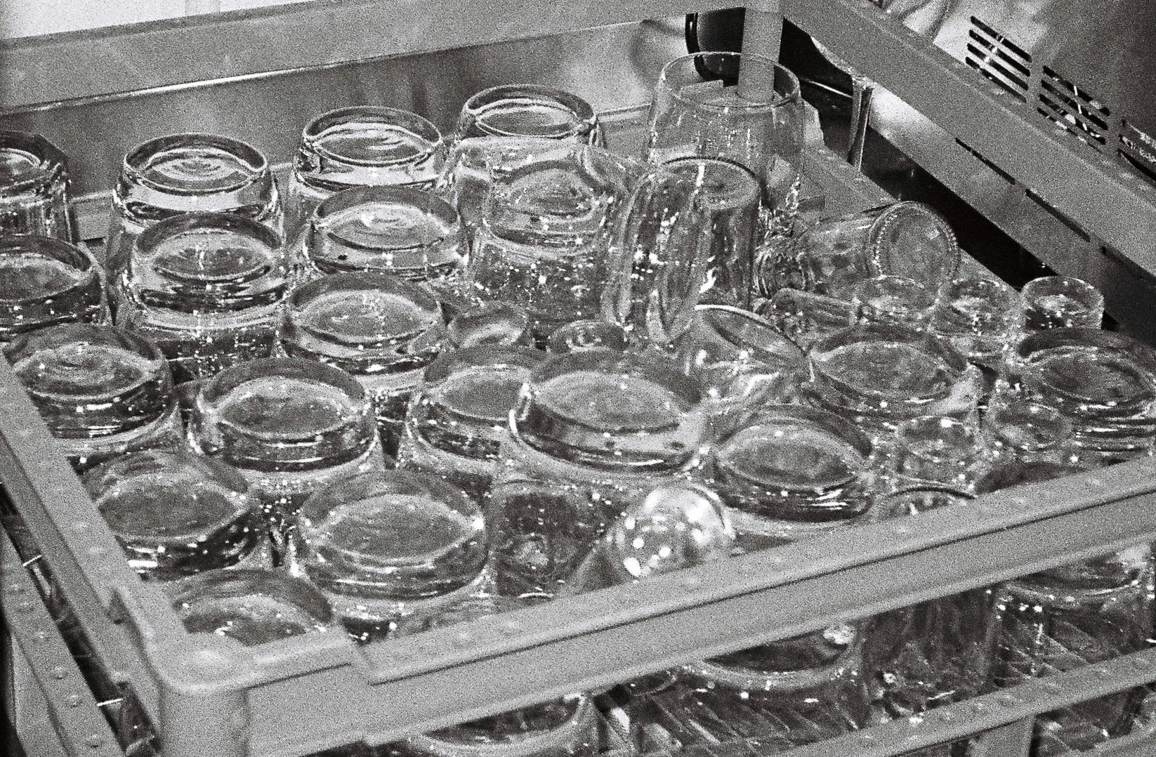 Dishwasher filled with stacked glass cups and glasses.