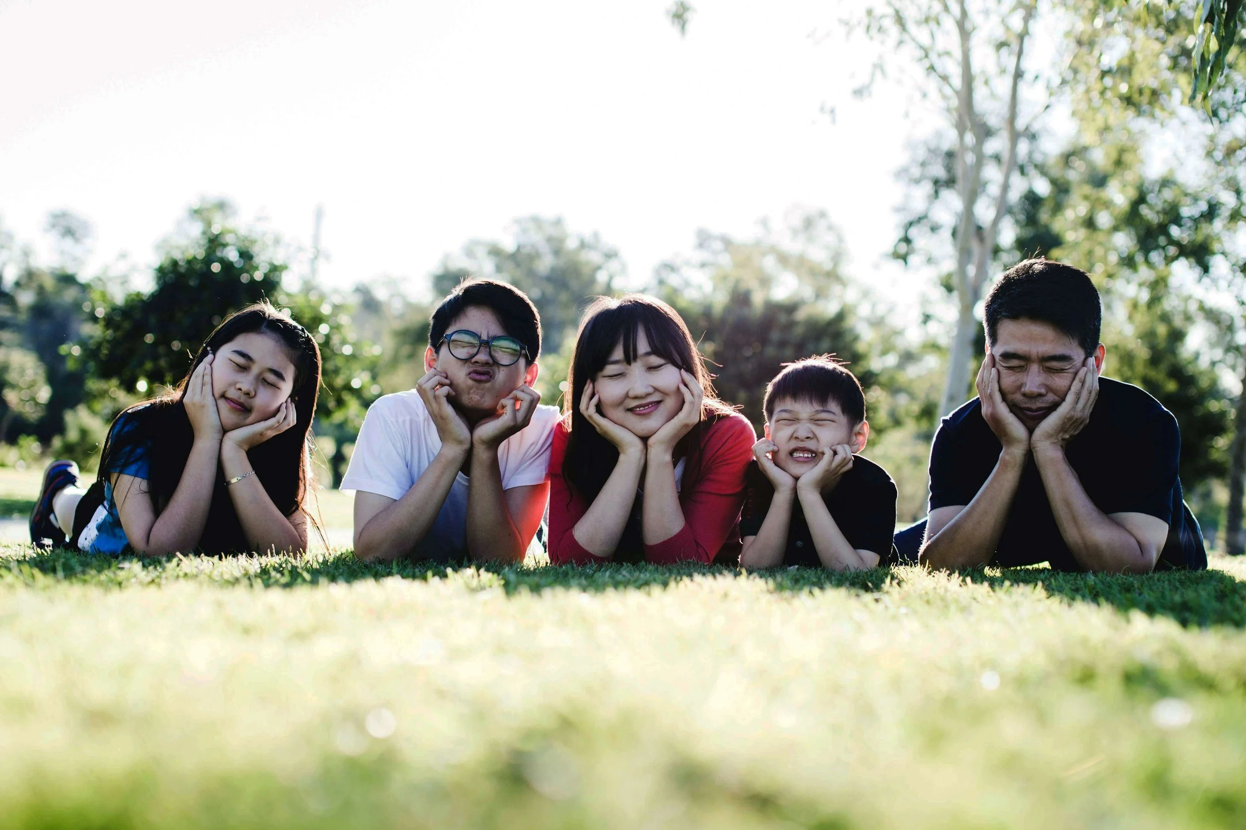 A family laying in the grass with their heads in their hands