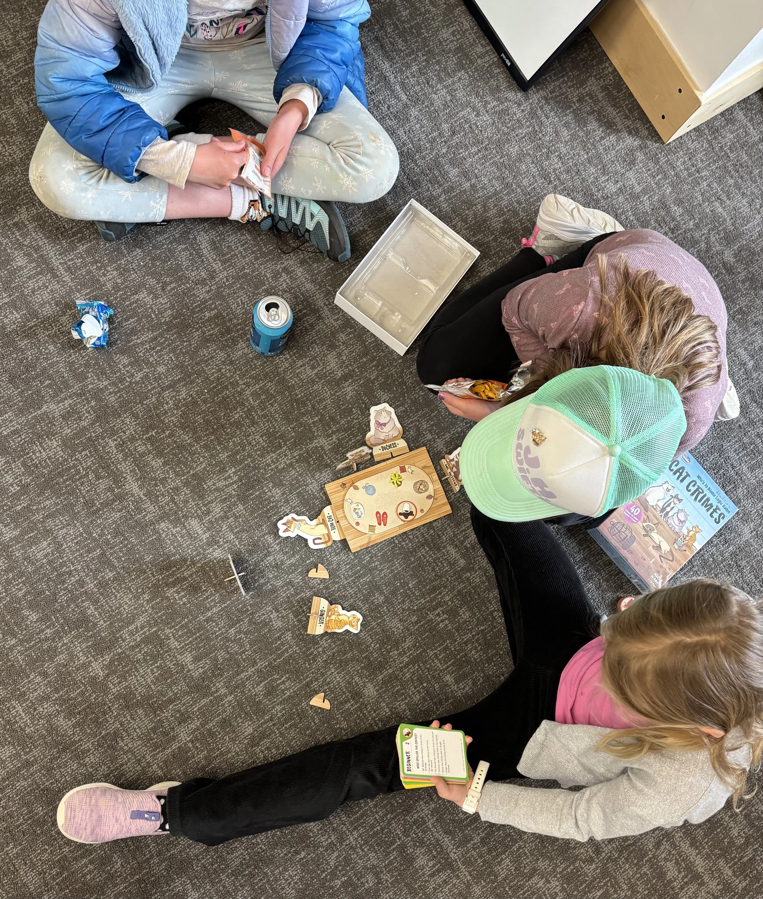 Photo shot from above showing a group of girls engaging in a game together while sitting on the floor