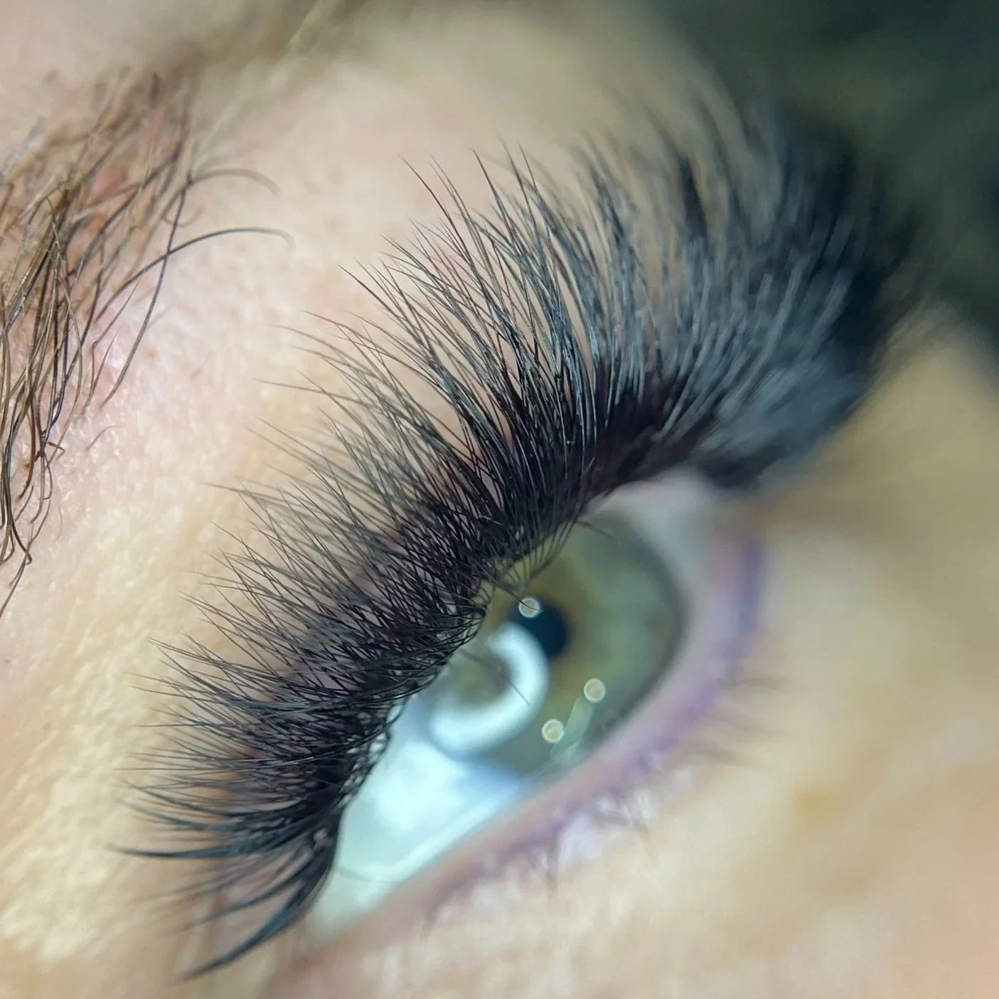 Close-up view of a person's eye with long, thick eyelashes.